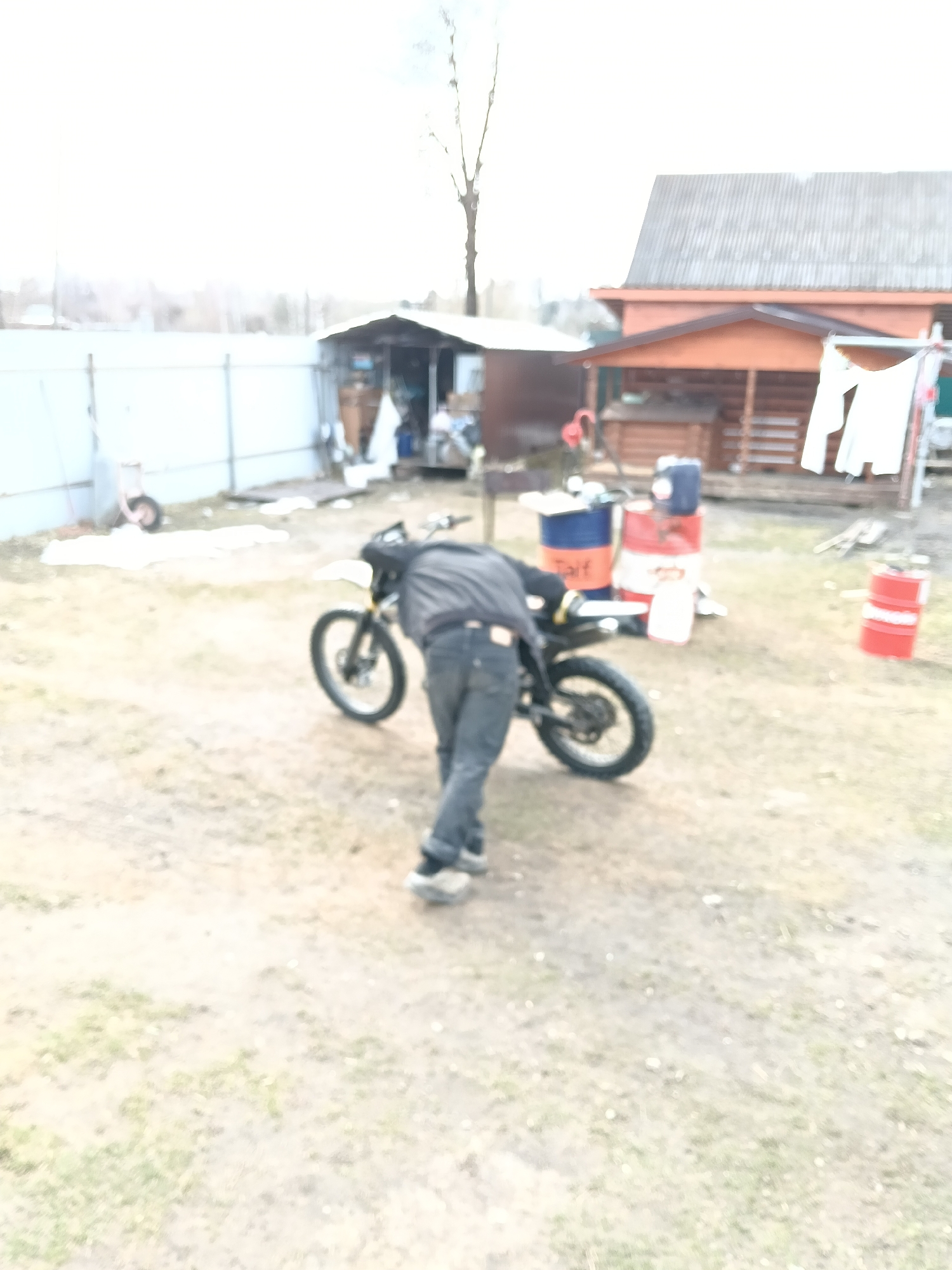 Person services motorcycle in Russian village yard