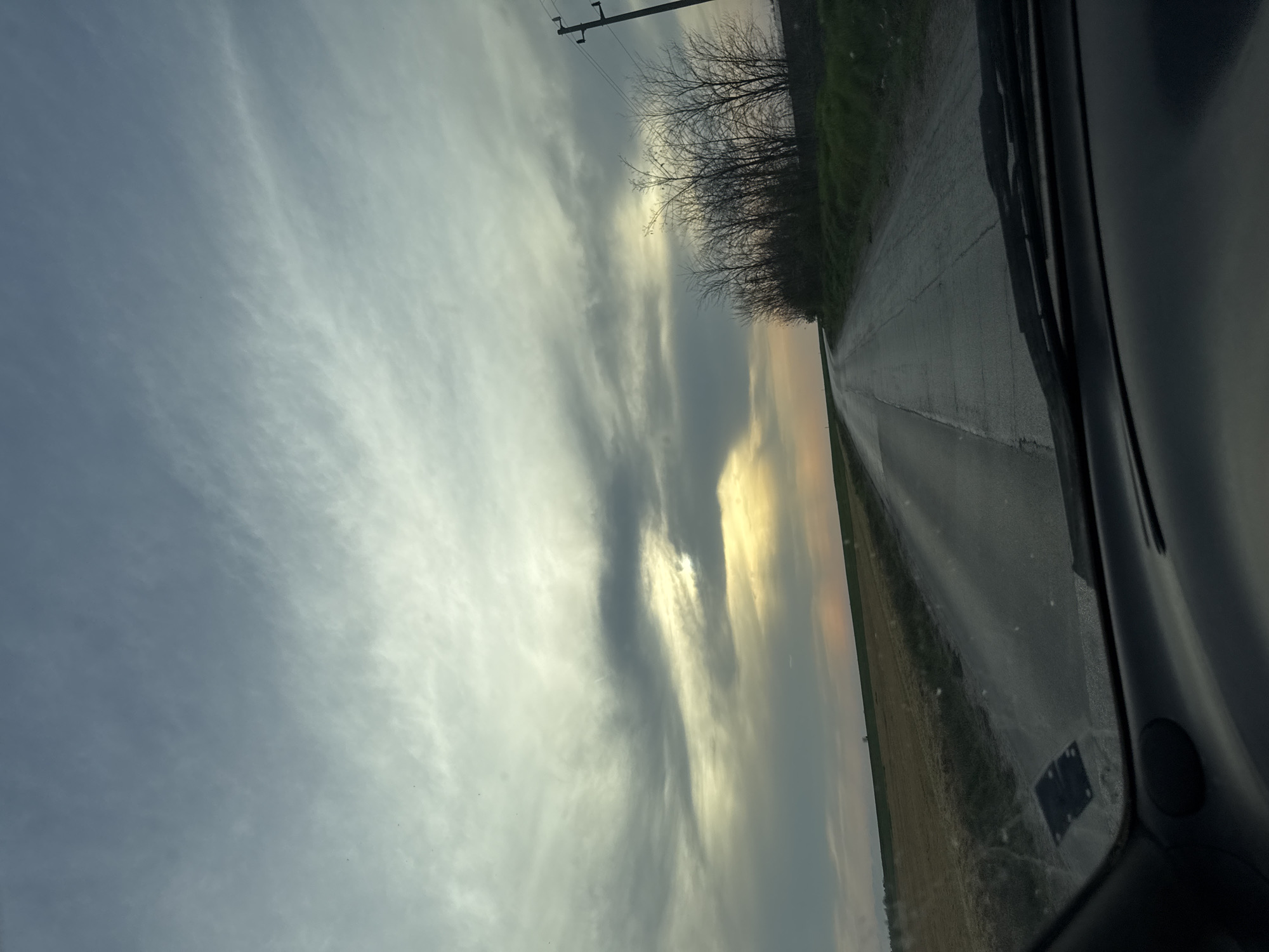 Motorist drives wet road through Bulgarian countryside fields