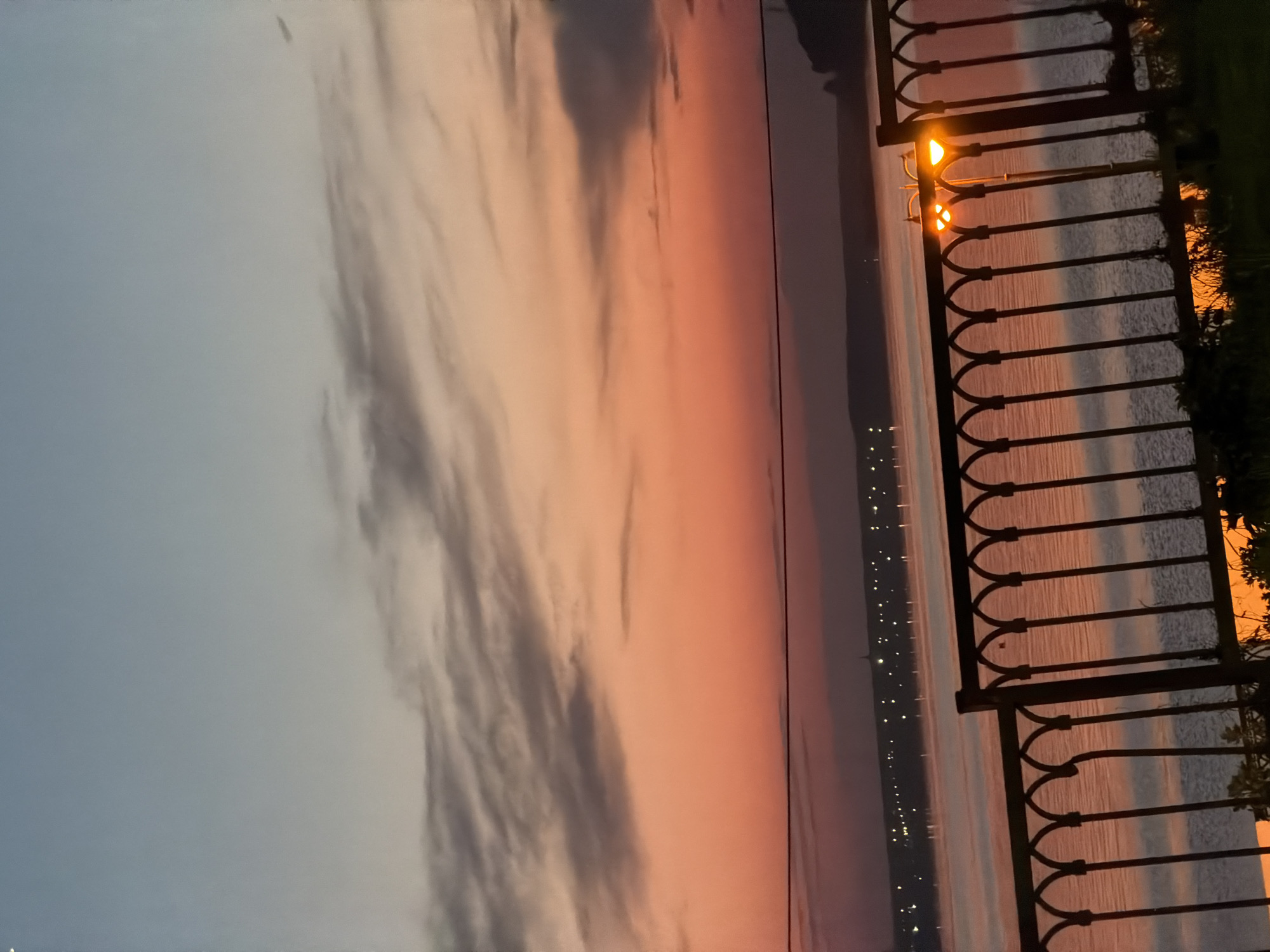 Sunset captured along Izhevsk waterfront with lampposts and fence