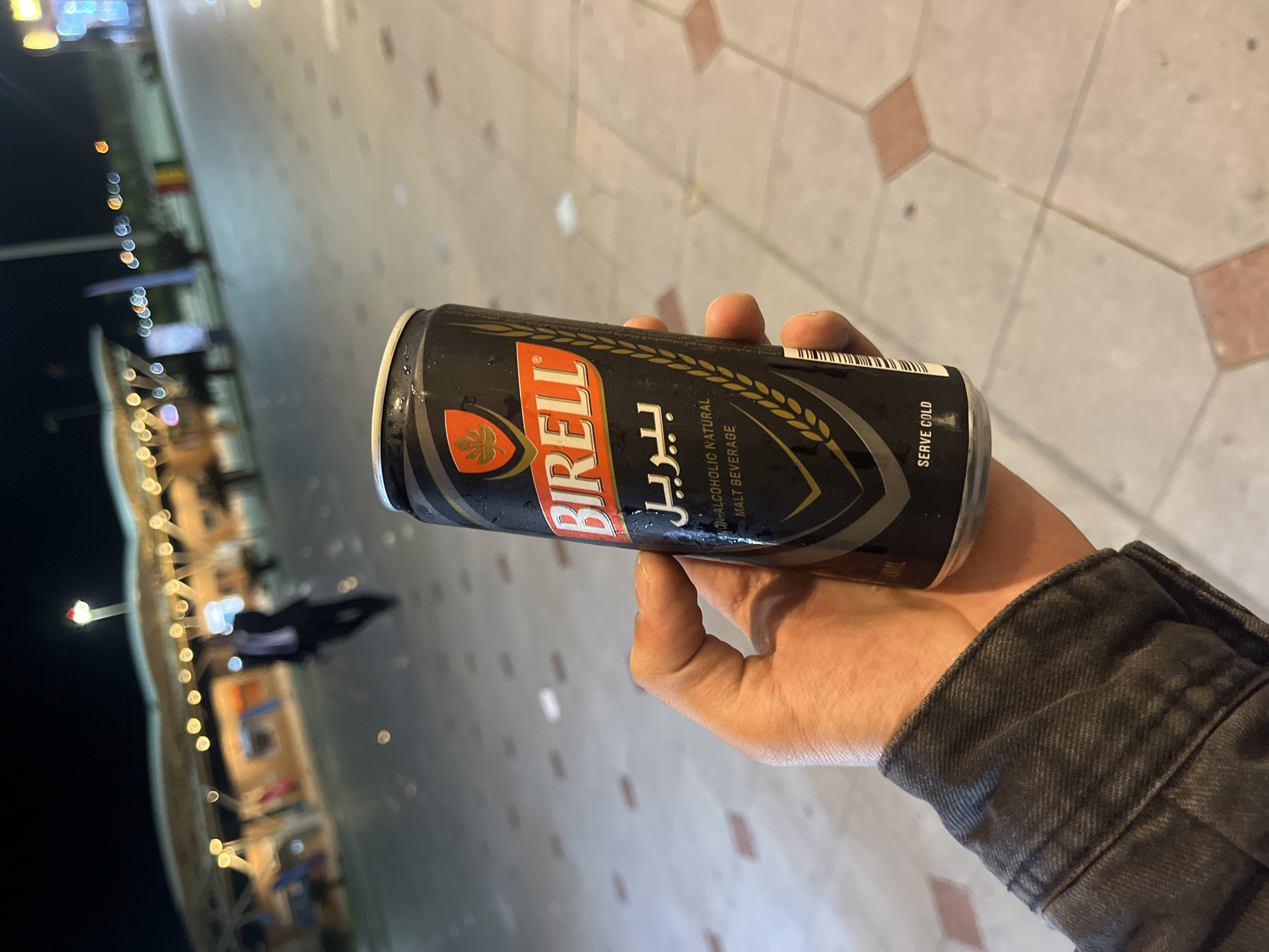 Person enjoys non-alcoholic beverage outdoors in Egyptian city at night