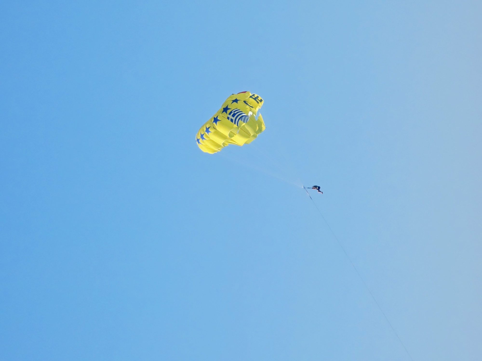 Parasailing over a busy Malia beach on a sunny afternoon