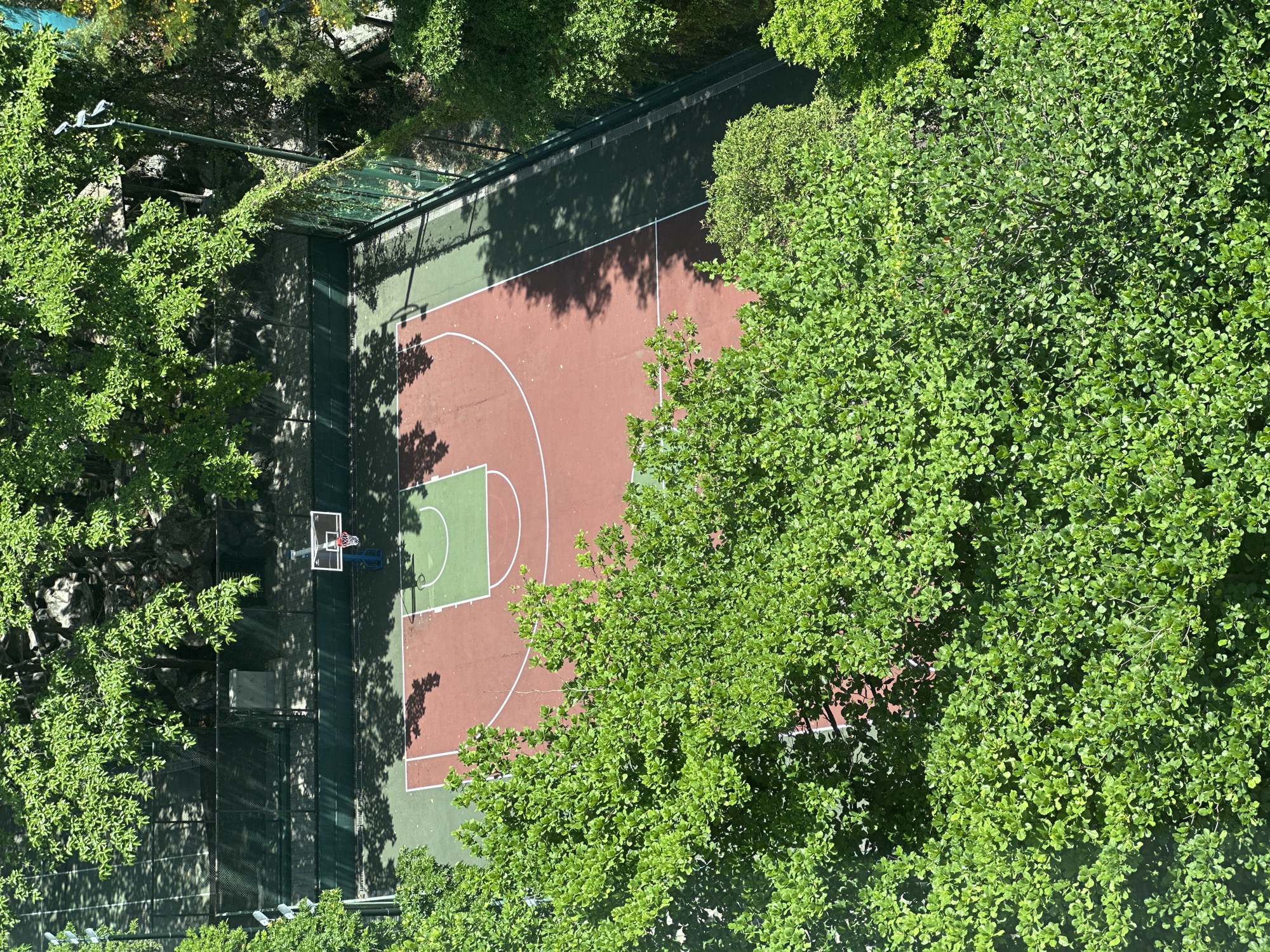 Aerial views show basketball court and hillside walkway in India