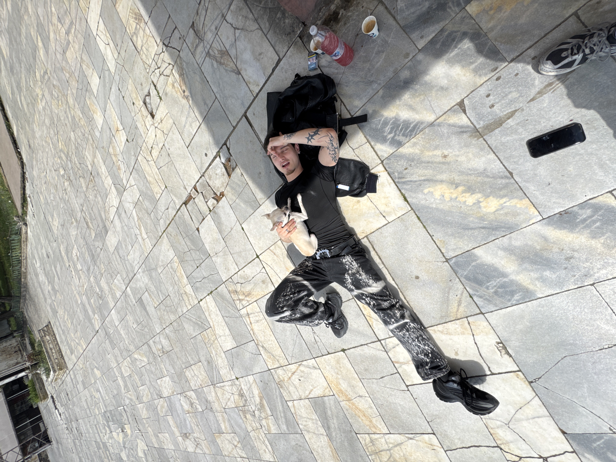 Man lies on pavement holding dog in Karlovo, Bulgaria
