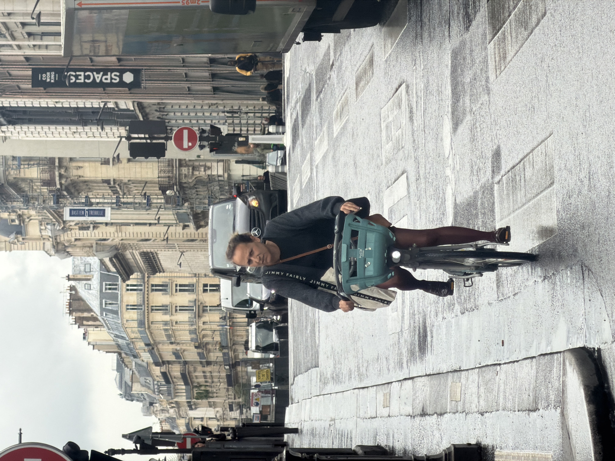 Cyclist navigates wet Paris streets amid classical architecture