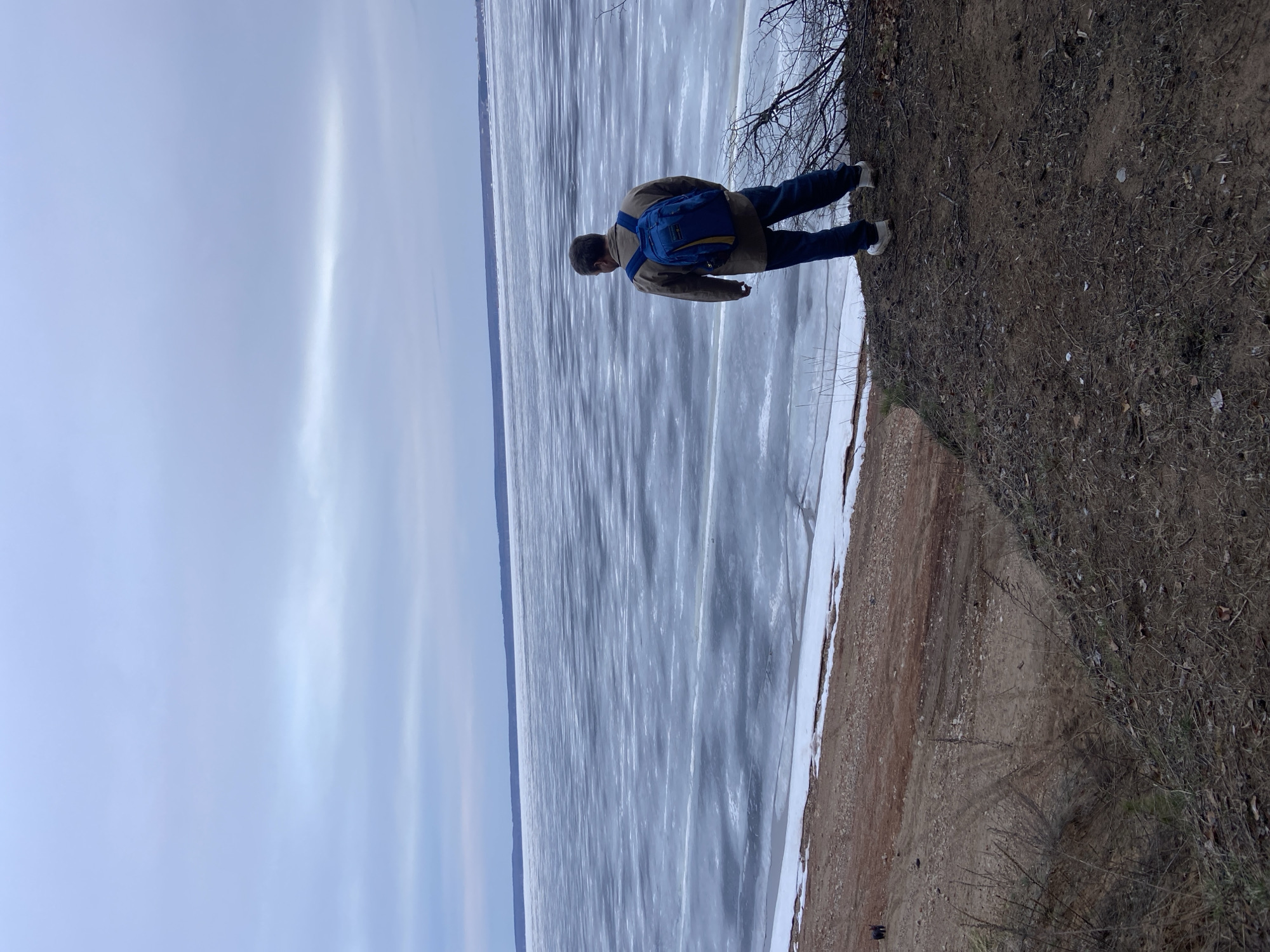 Man observes frozen waterway from embankment in Noviy, Russia