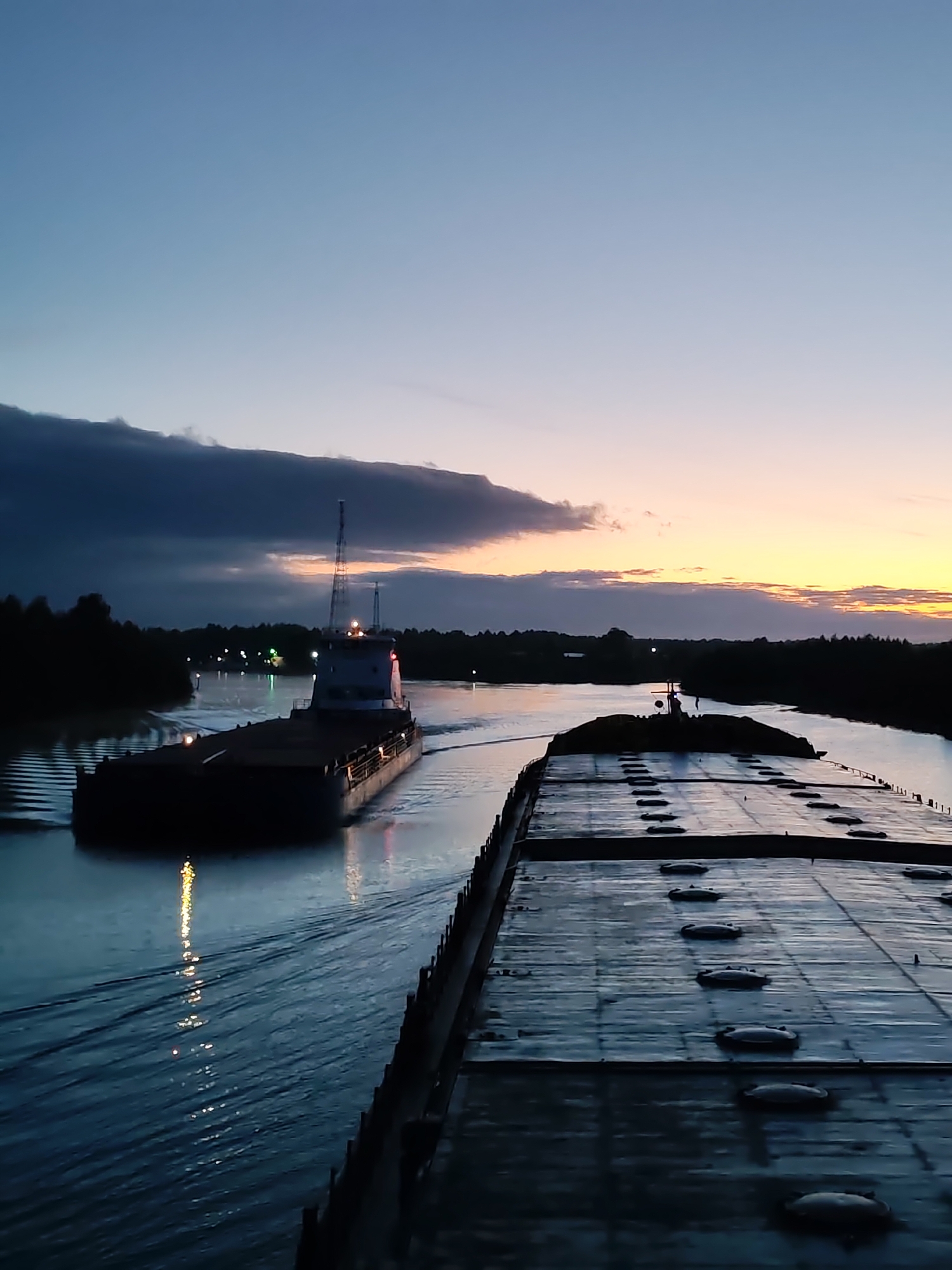 Commercial barges navigate Russian waterways at sunset near Annensky Most