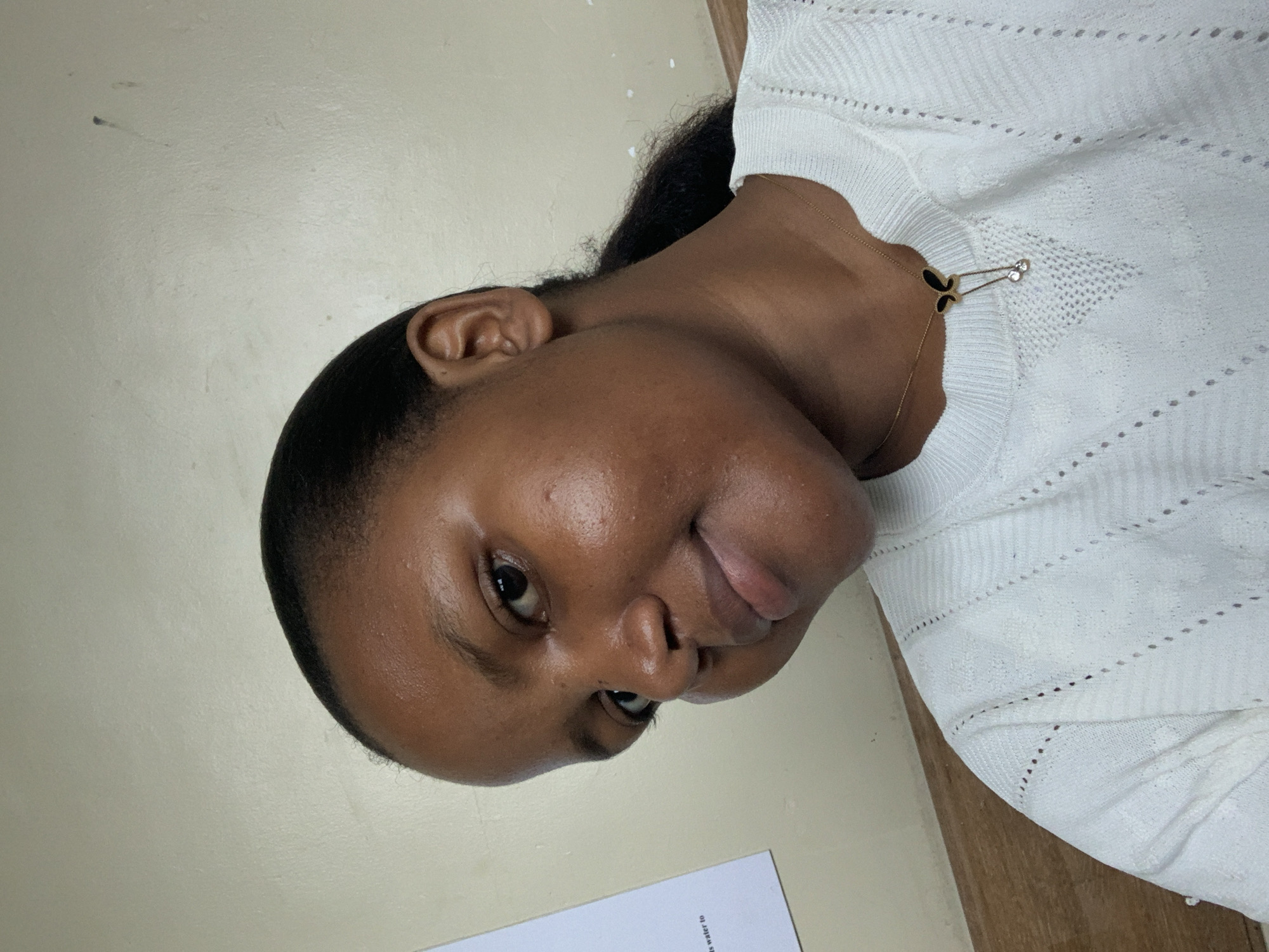 Woman photographed indoors in Dar es Salaam wearing butterfly necklace
