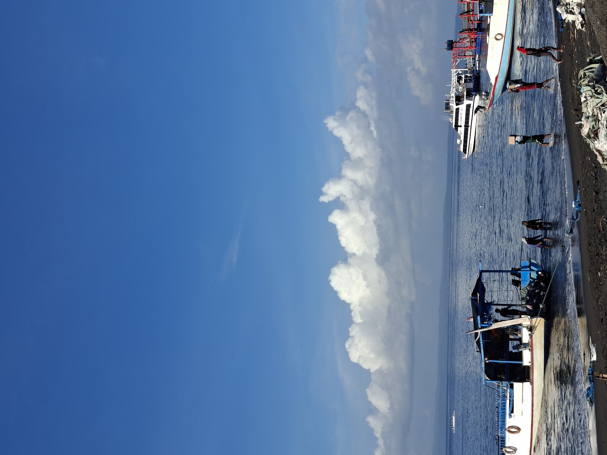 Boats, pier activity, and open water at Dawan's coast