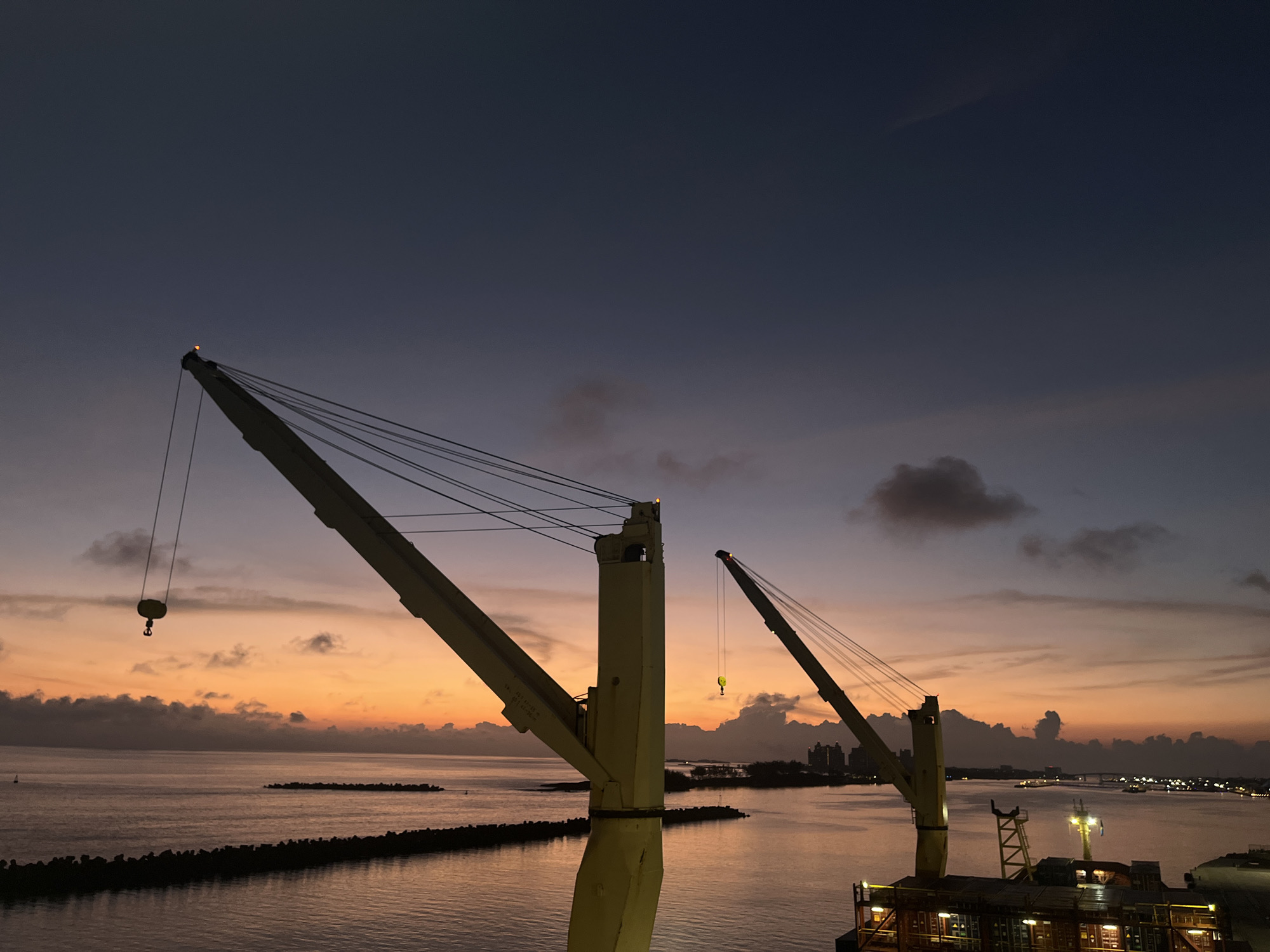 Industrial cranes captured against colorful sky at waterfront location