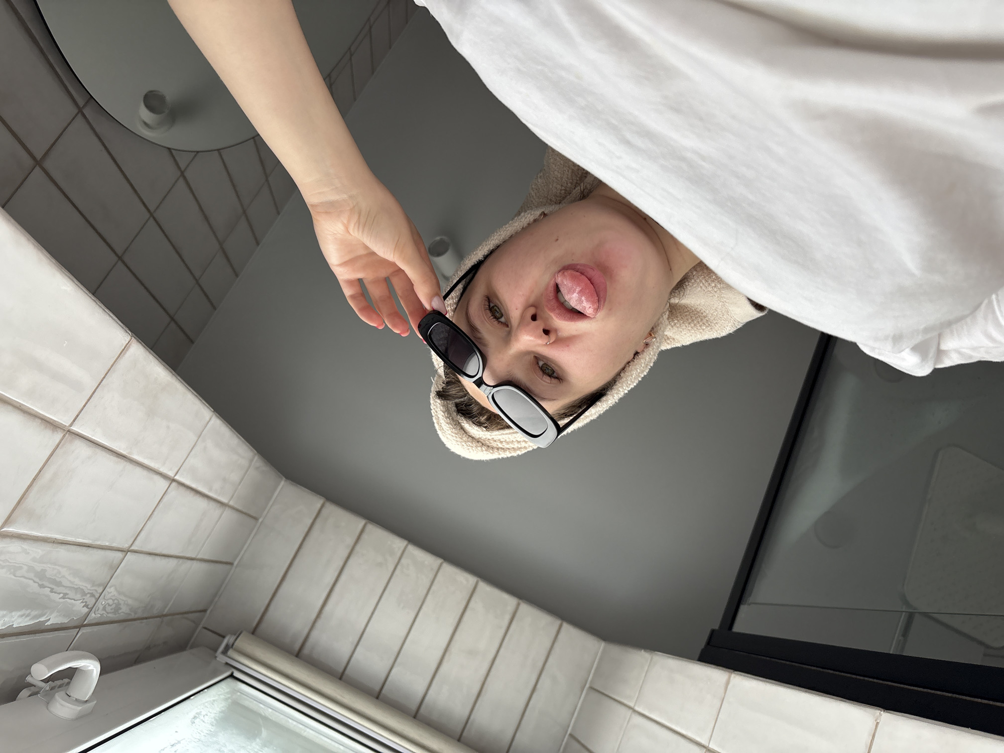 Person poses with towel and sunglasses in Izhevsk bathroom