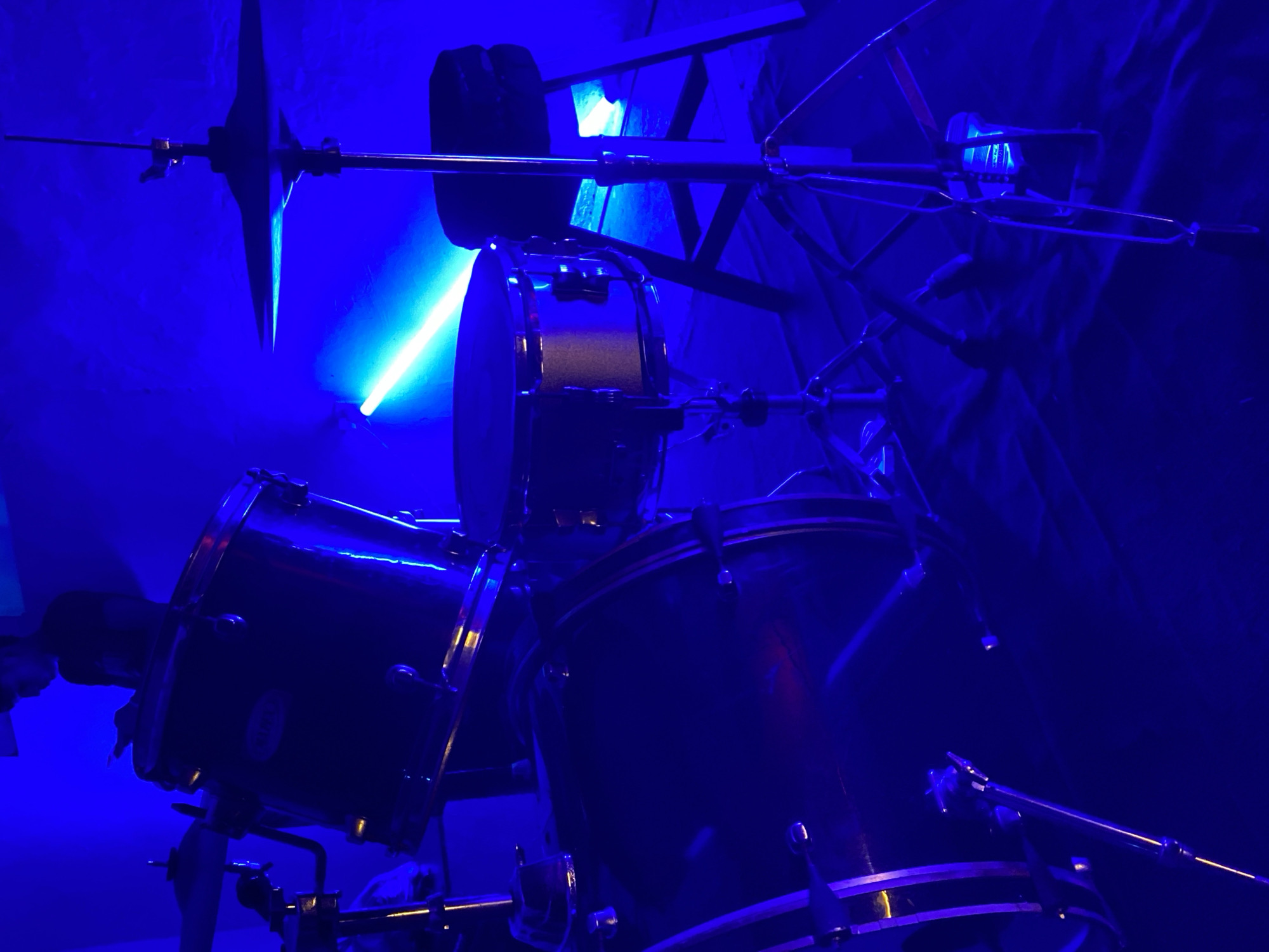 Drum set captured under blue lighting in Tinaquillo room
