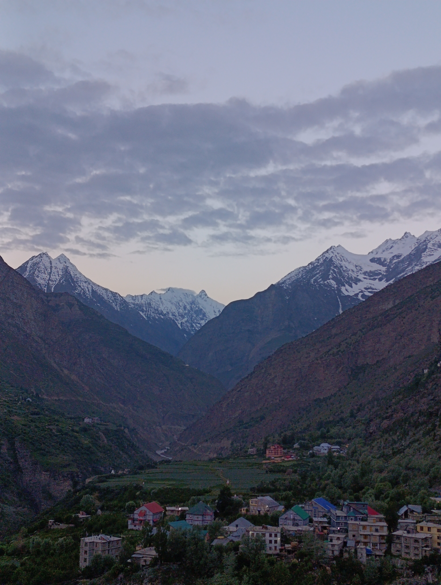 Keylong village and a hillside guesthouse beneath snowy Himalayan peaks
