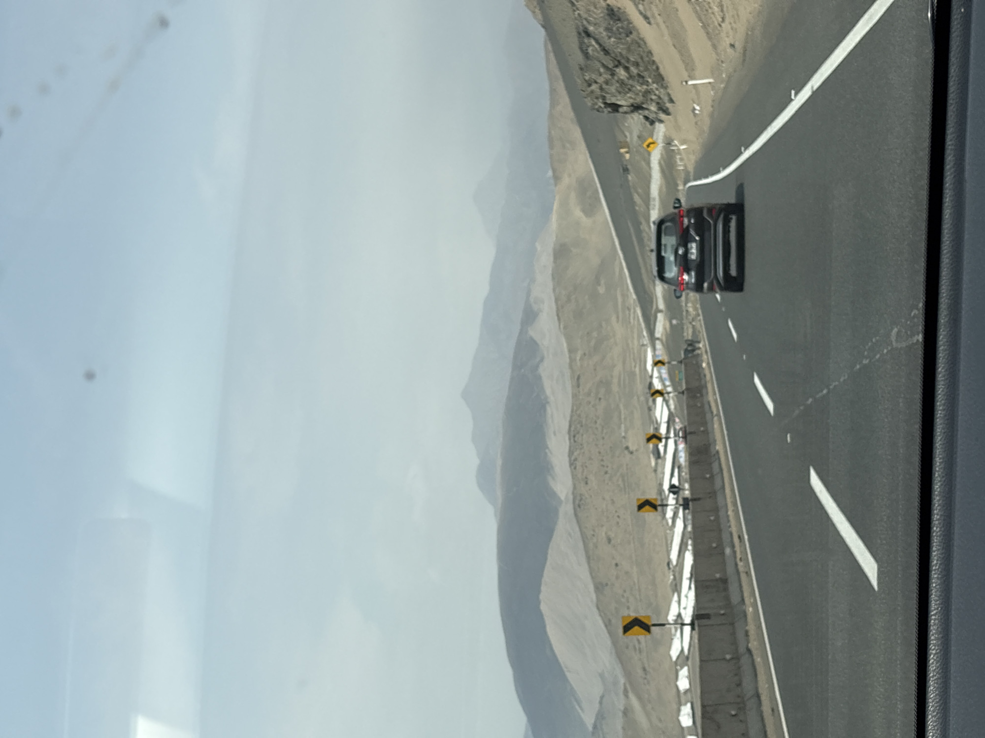 Black car travels road with barriers in Aucallama Peru