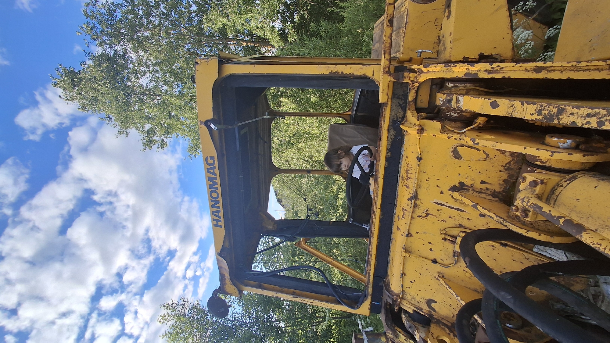 Kid plays in abandoned yellow loader in rural Russian field
