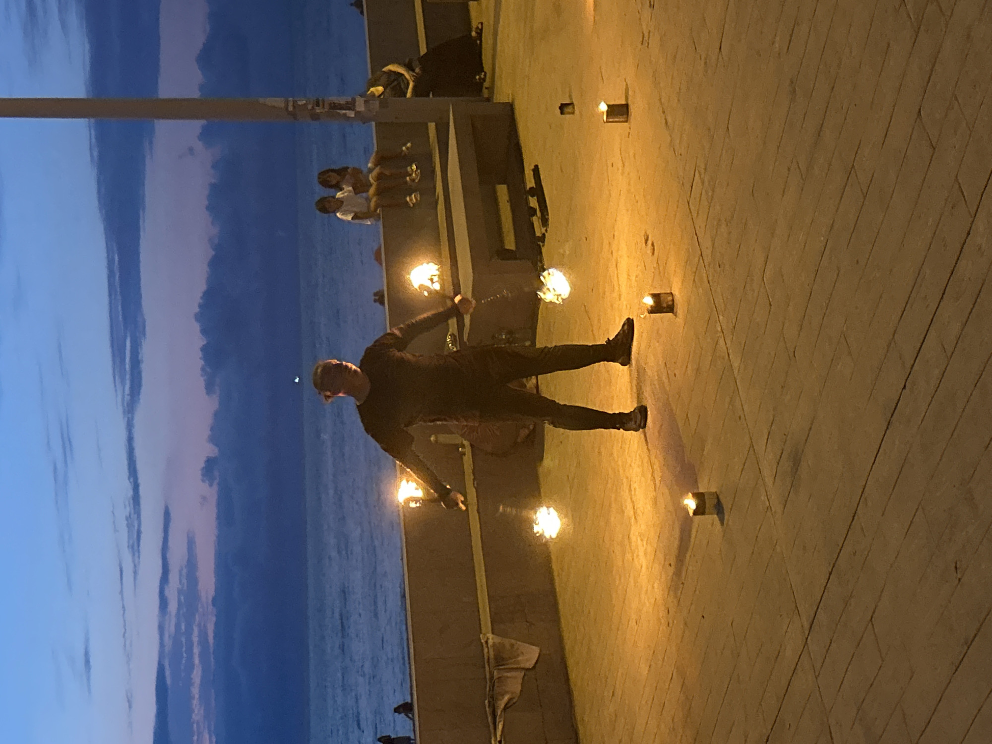 Fire performer works Batumi's waterfront promenade at dusk