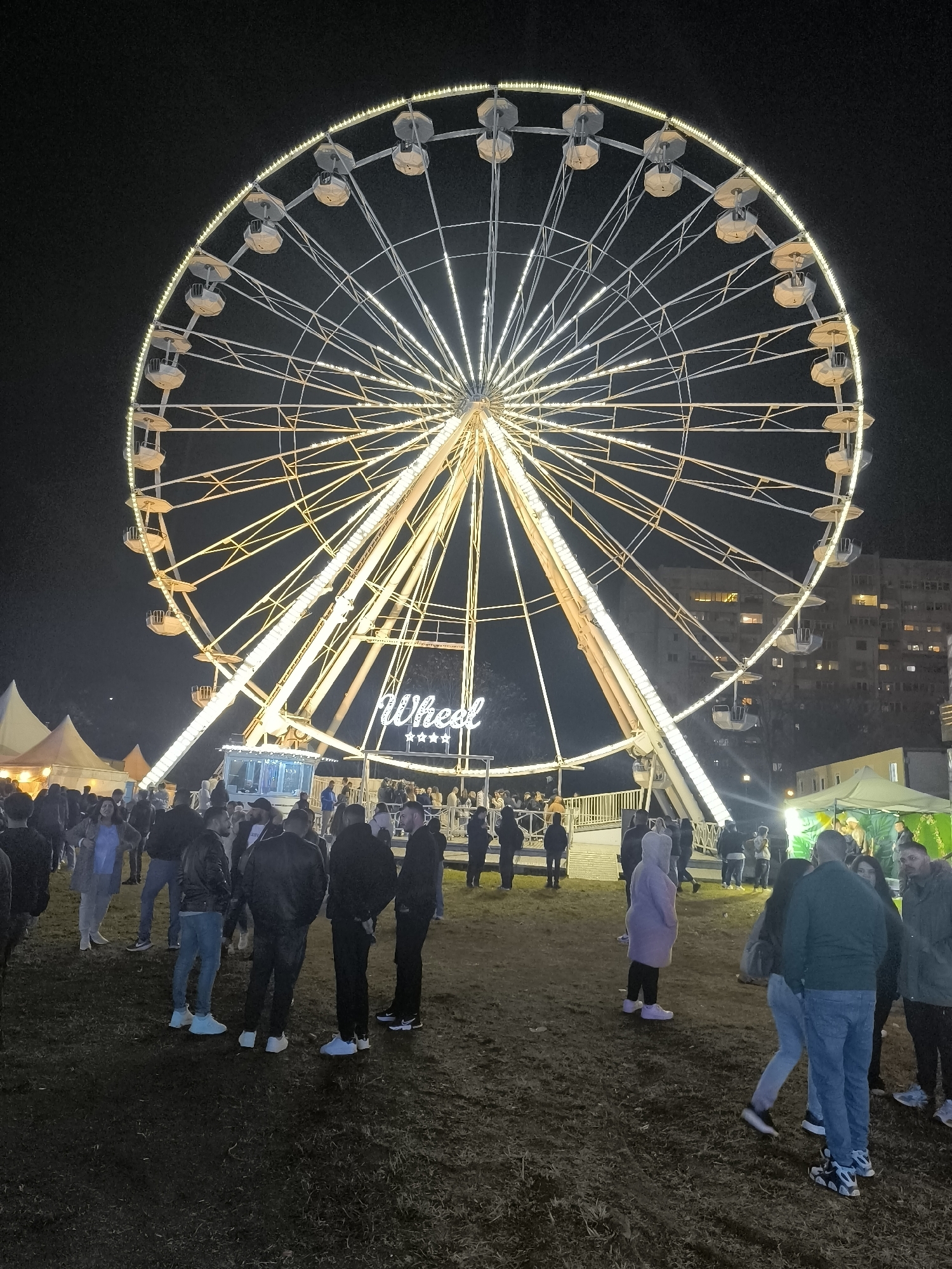 Illuminated Ferris wheel draws nighttime crowds at unknown fair