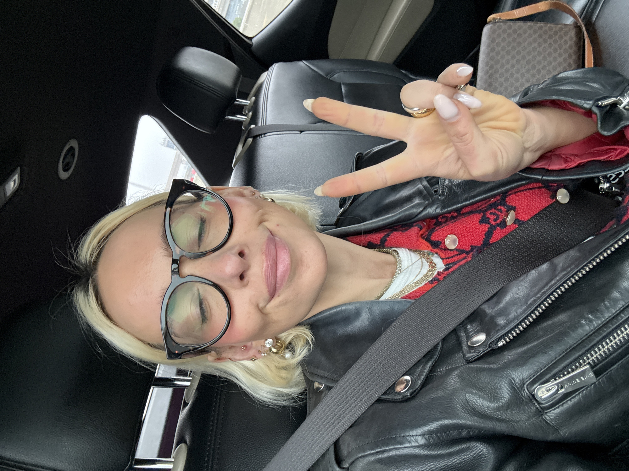 Woman makes peace sign gesture while seated in car