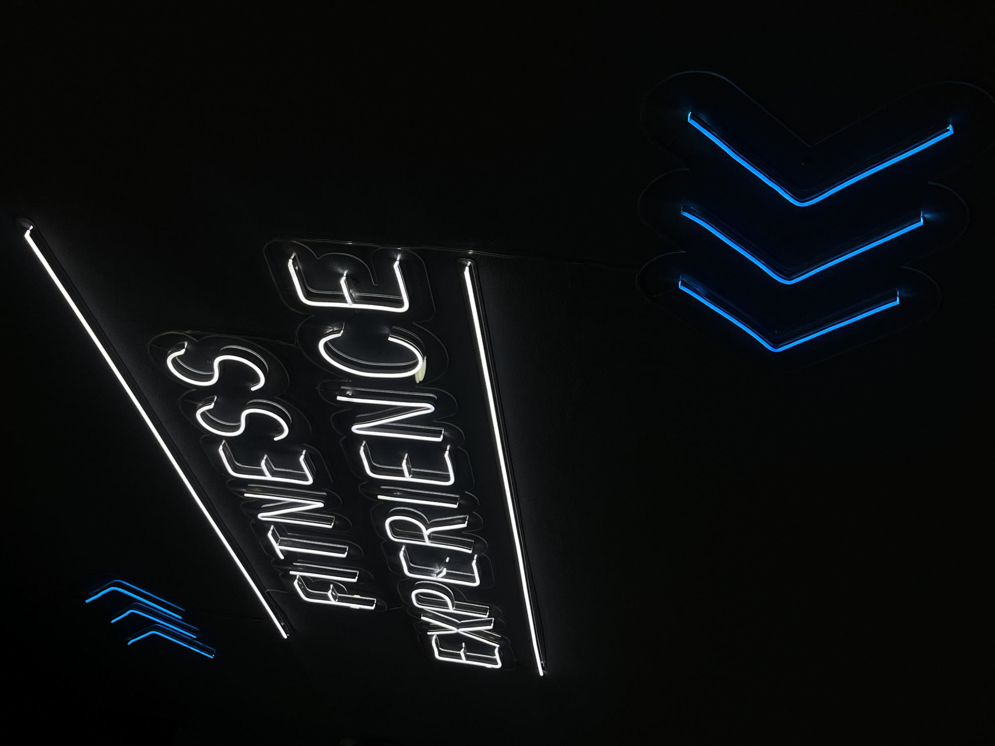 Neon fitness center sign observed in dark setting