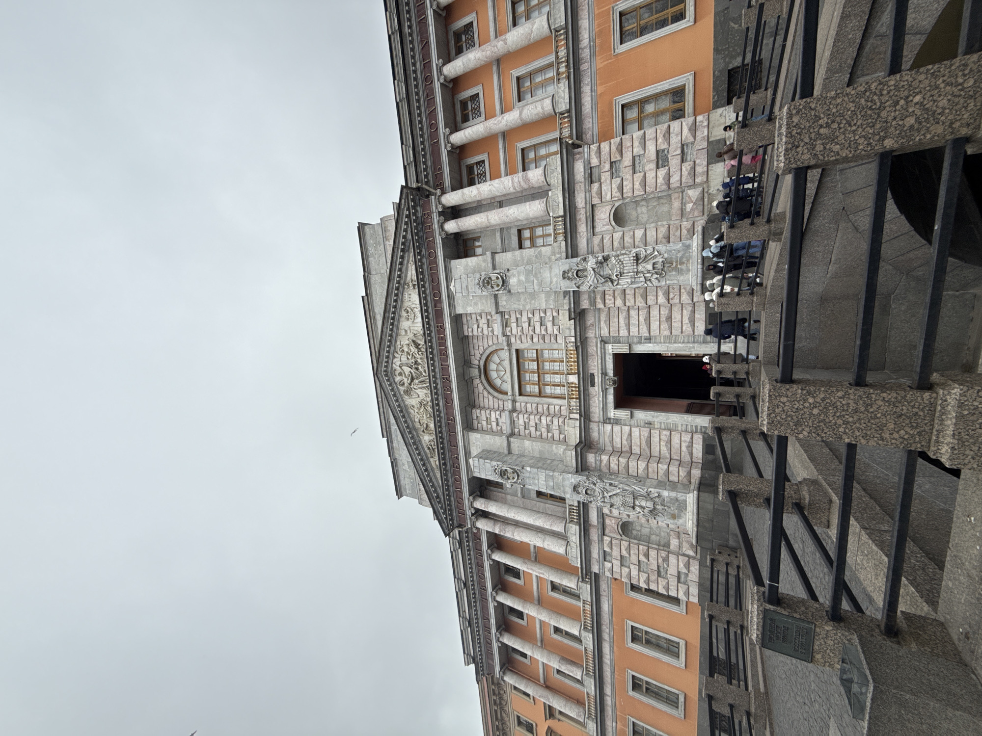 Tourist photographs historic Saint Petersburg landmarks under cloudy skies