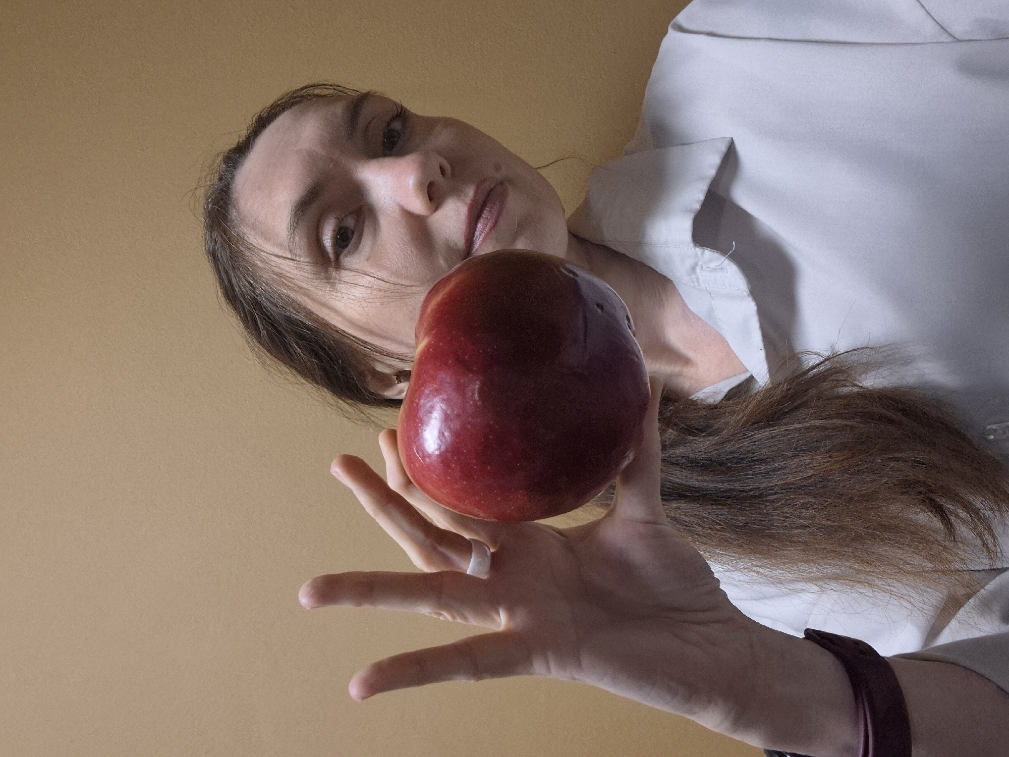 Woman photographed holding red apple from low angle perspective