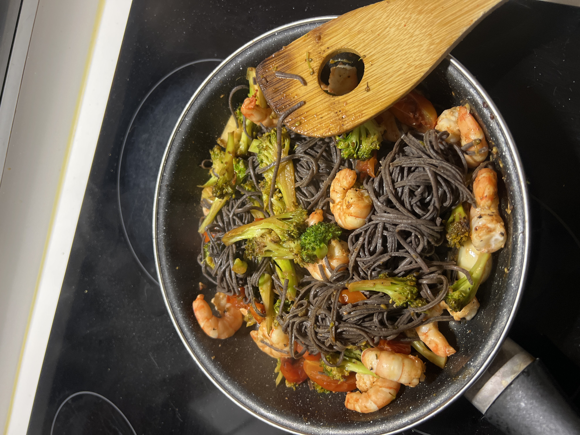 Woman documents cooking dark pasta meal in Paris kitchen