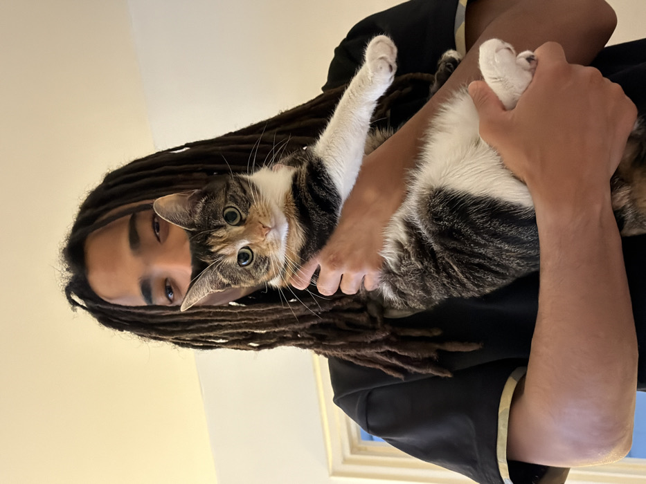 Person with dreadlocks holds mixed-color cat in Paris