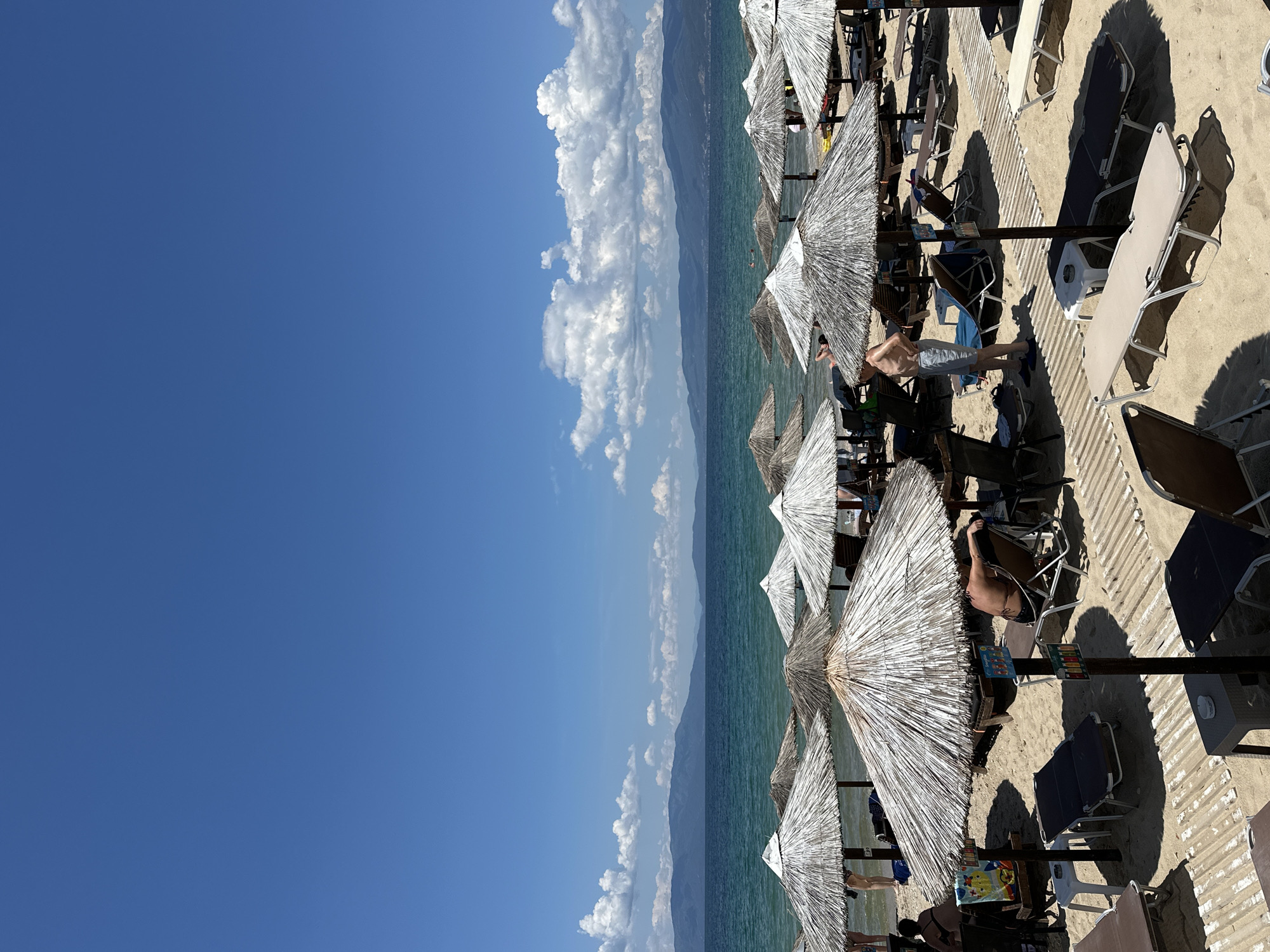 Crowded summer morning scene captured at Ofrynio Beach, Greece