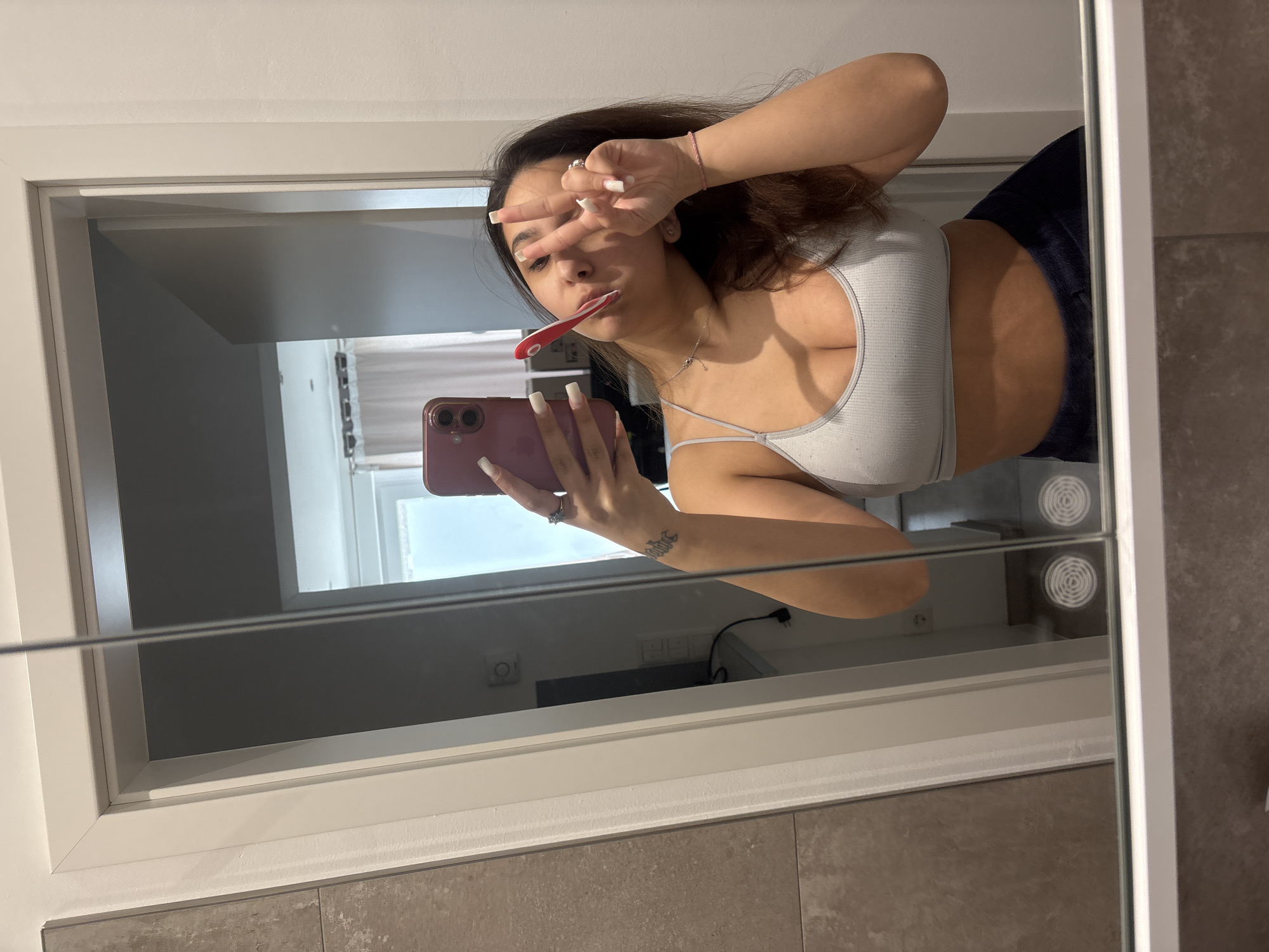 Woman takes mirror selfie while brushing teeth in Germany