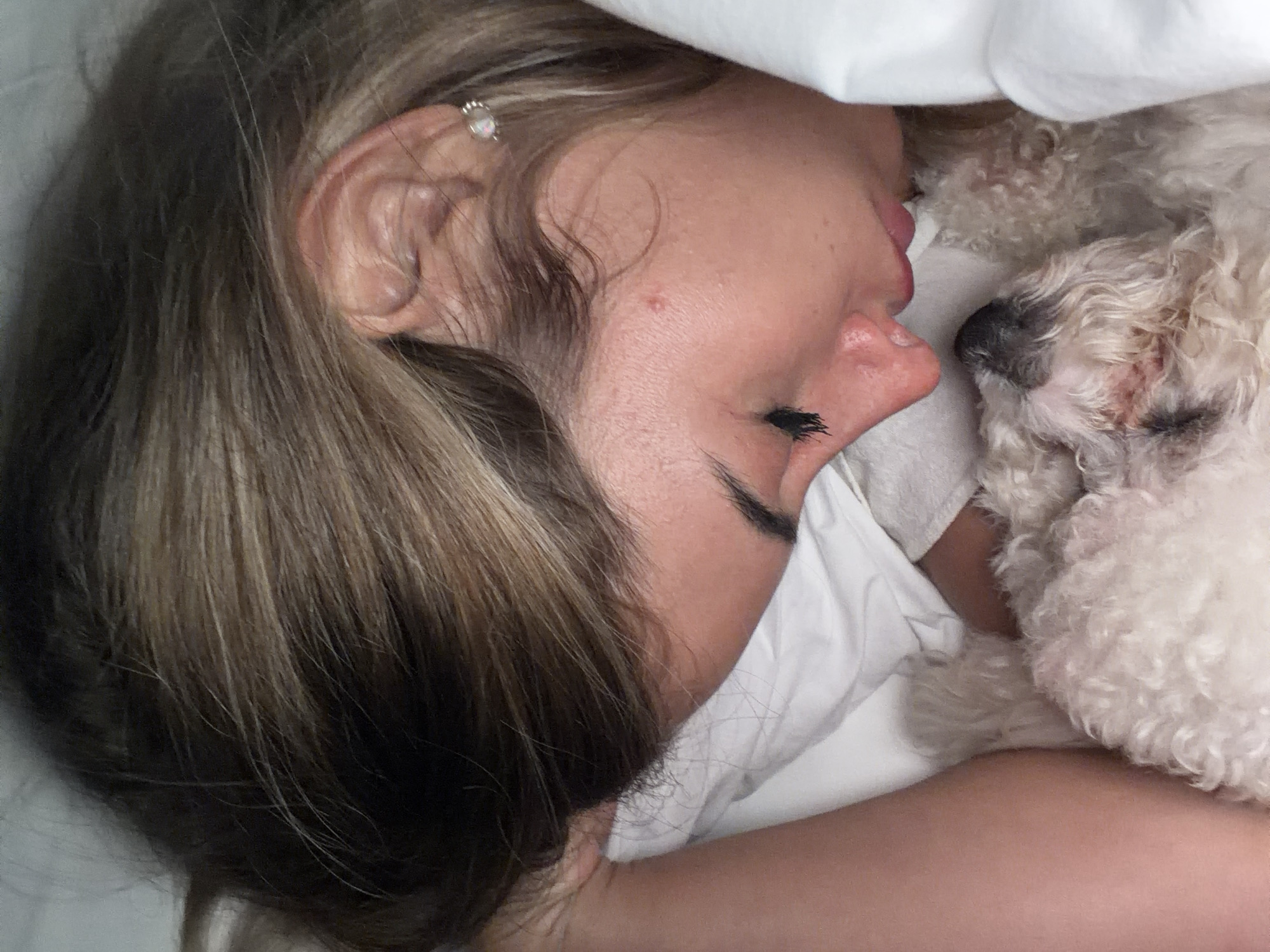 Woman and white dog share afternoon nap in Kedewatan