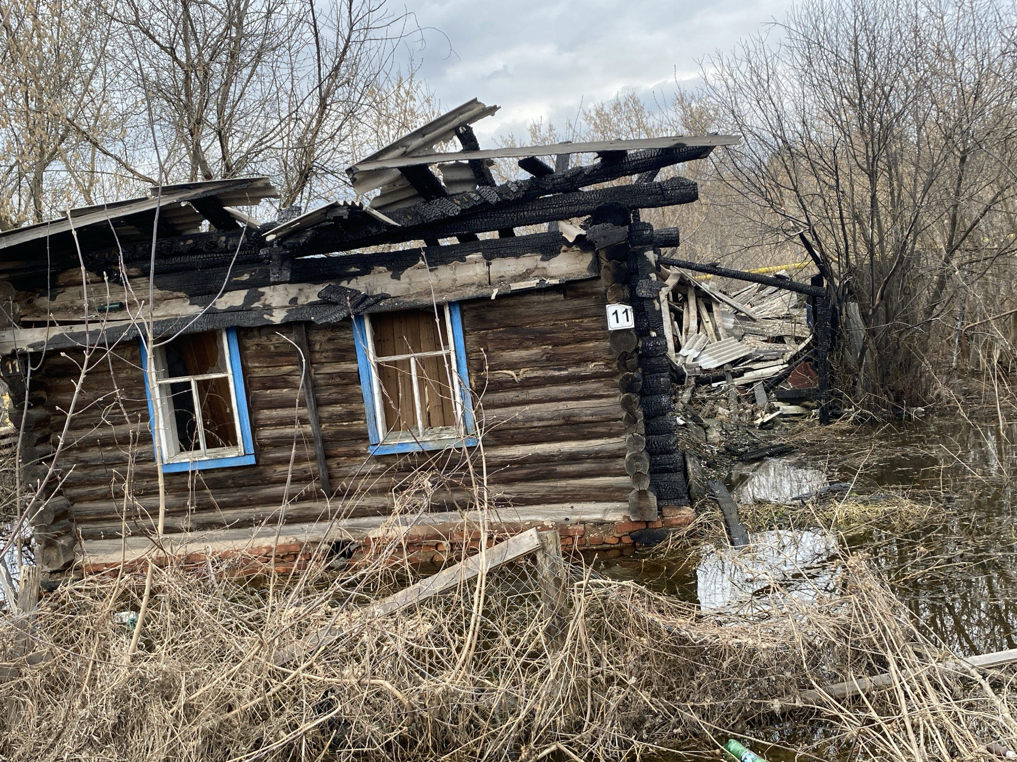 Fire-damaged wooden ruins observed in flooded Pozim' area