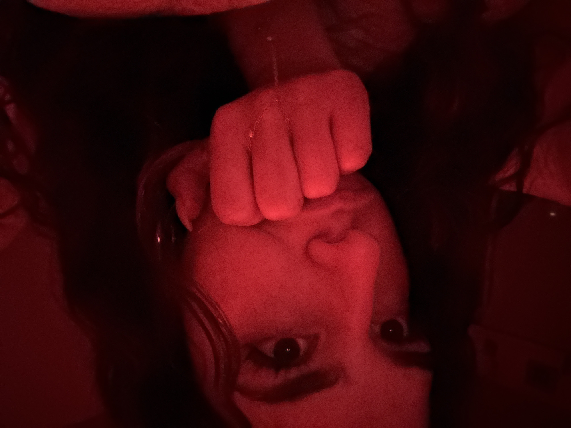 Close-up photo shows face below fist with hanging chain