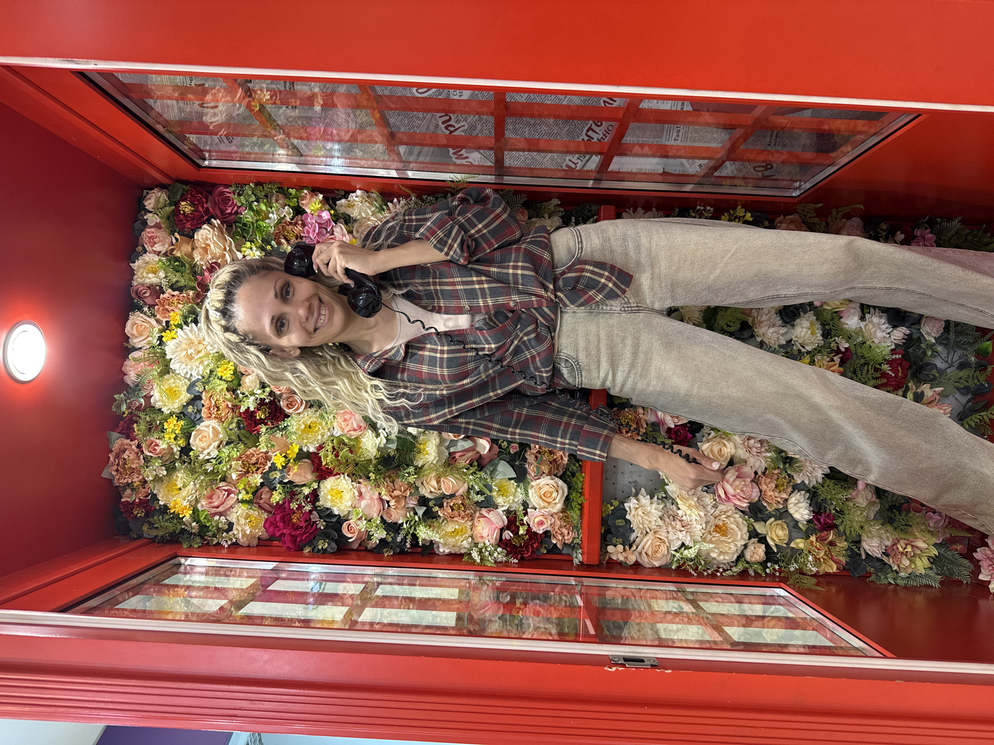 Woman poses with flowers in decorated phone booth