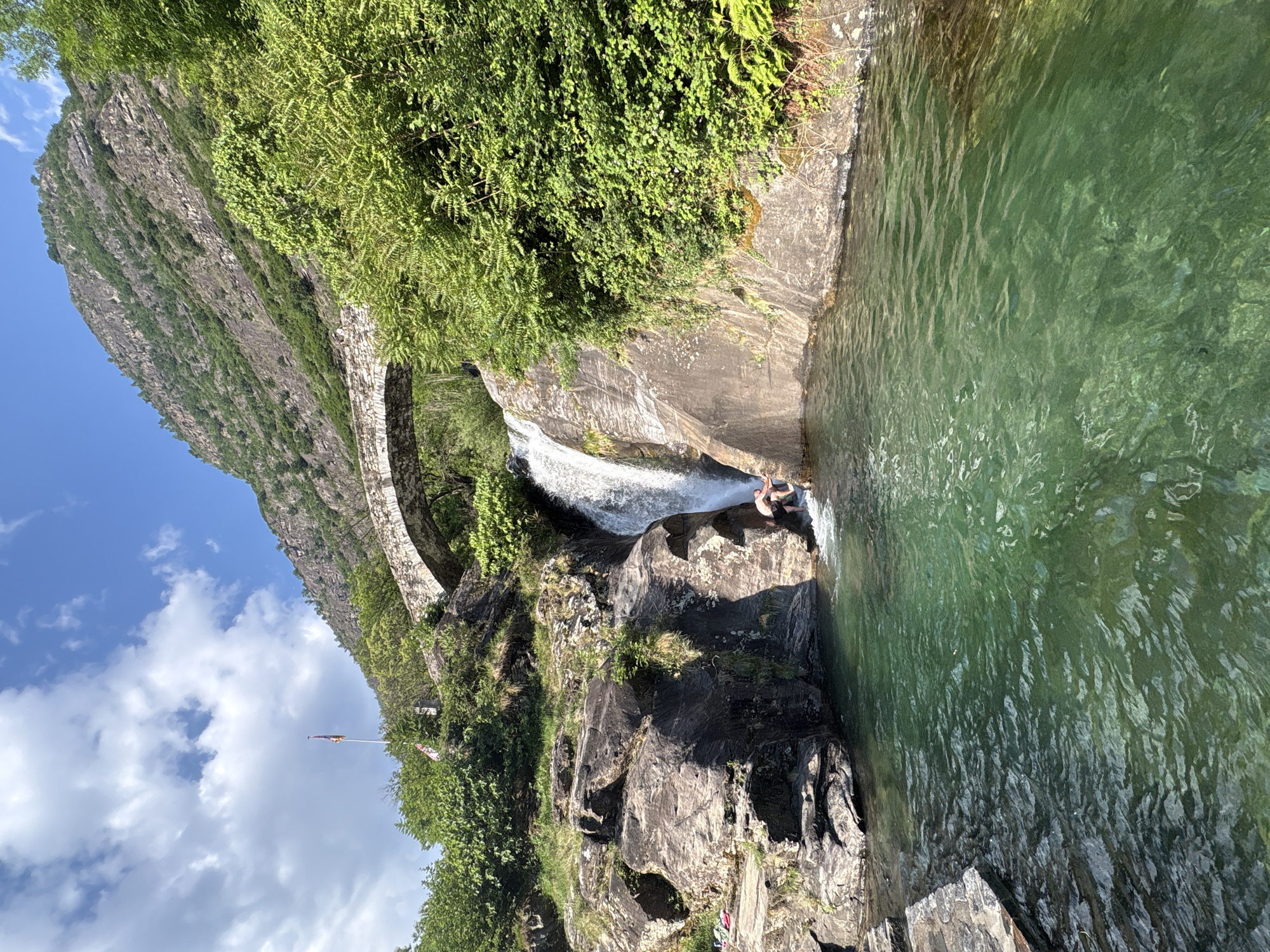 Person enjoys waterfall swim at Biasca rock formation