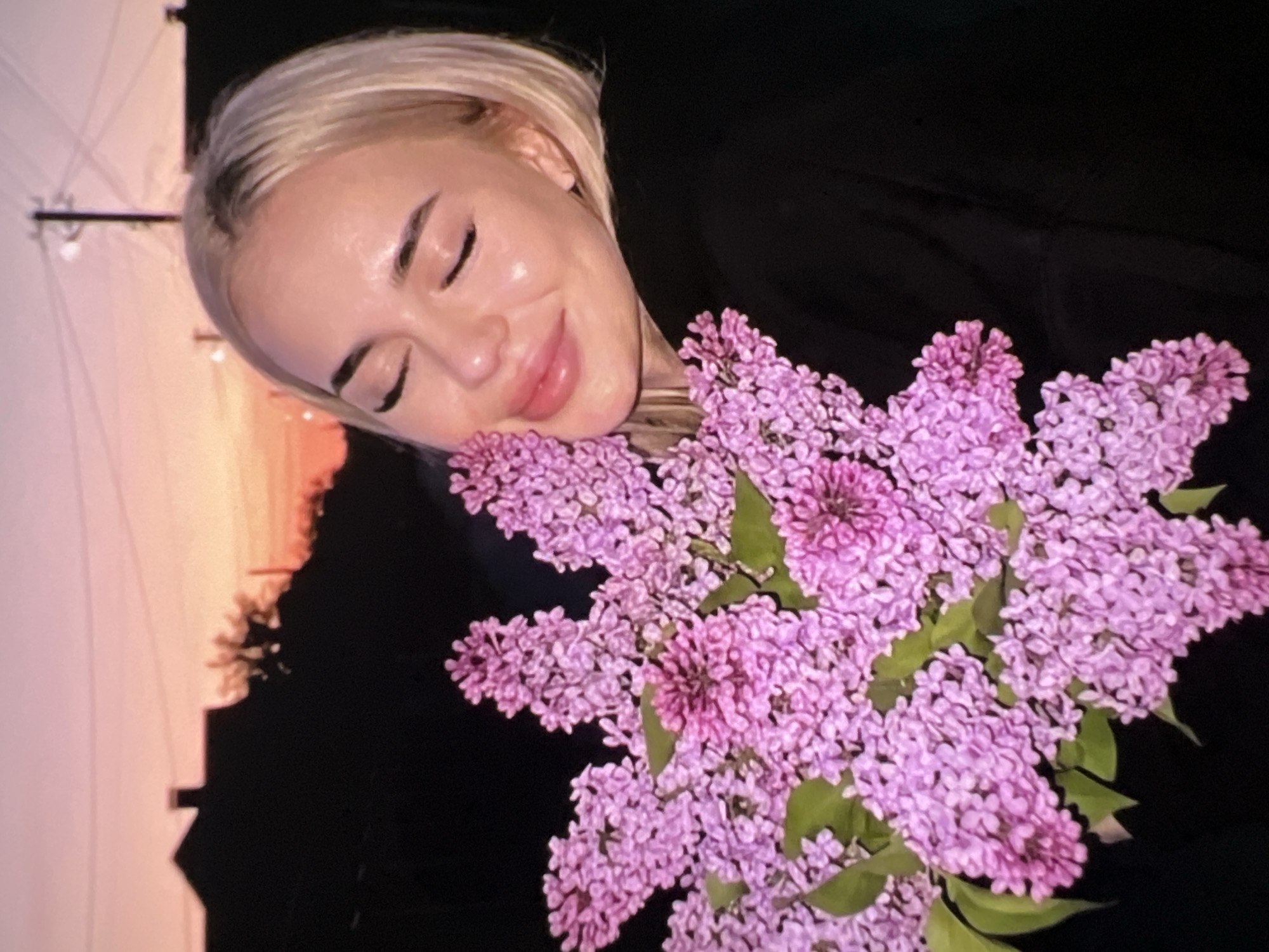 Woman poses with lilac flowers in peaceful portrait session