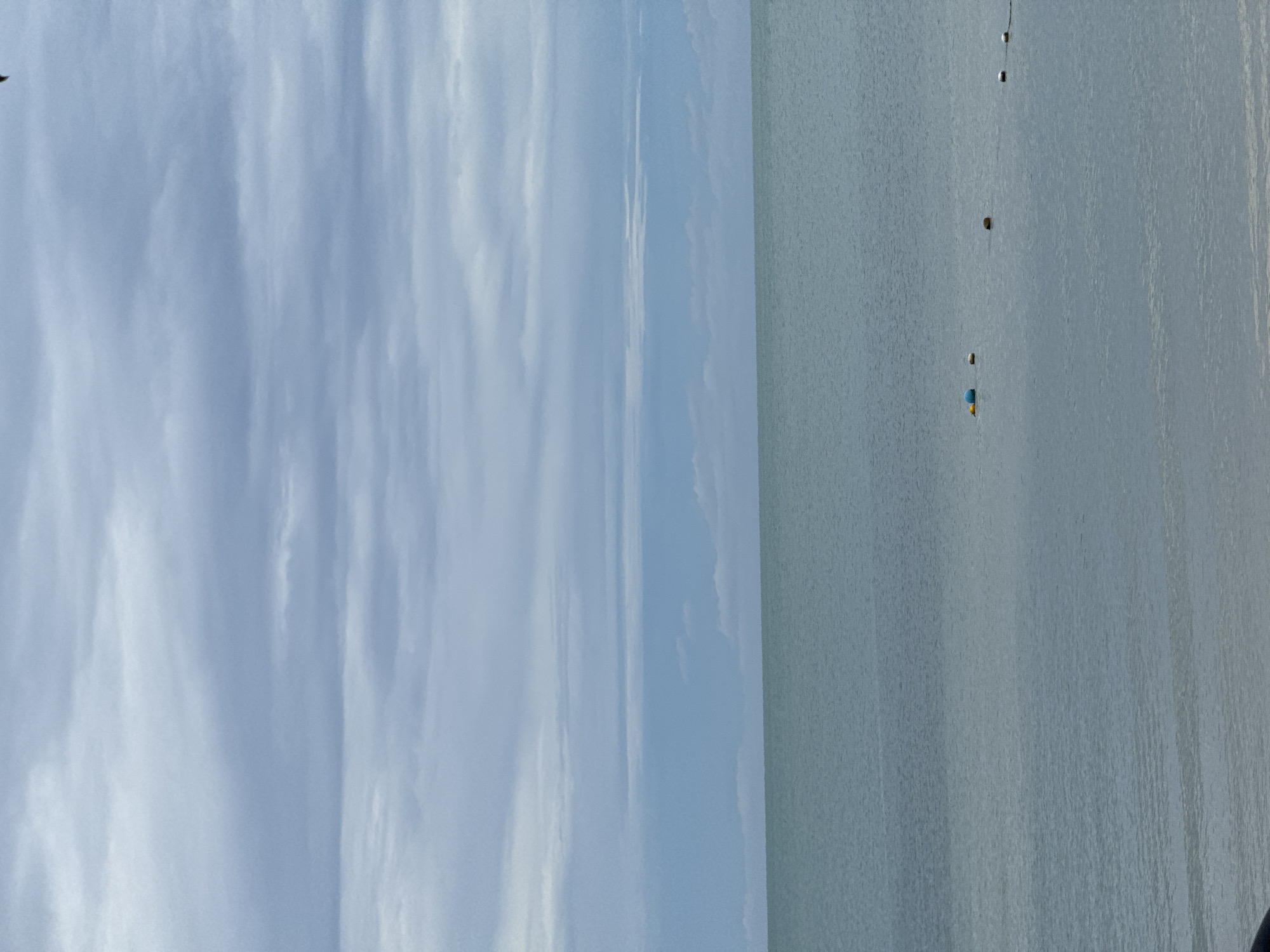 Calm coastal day with boats, beaches, and overcast skies