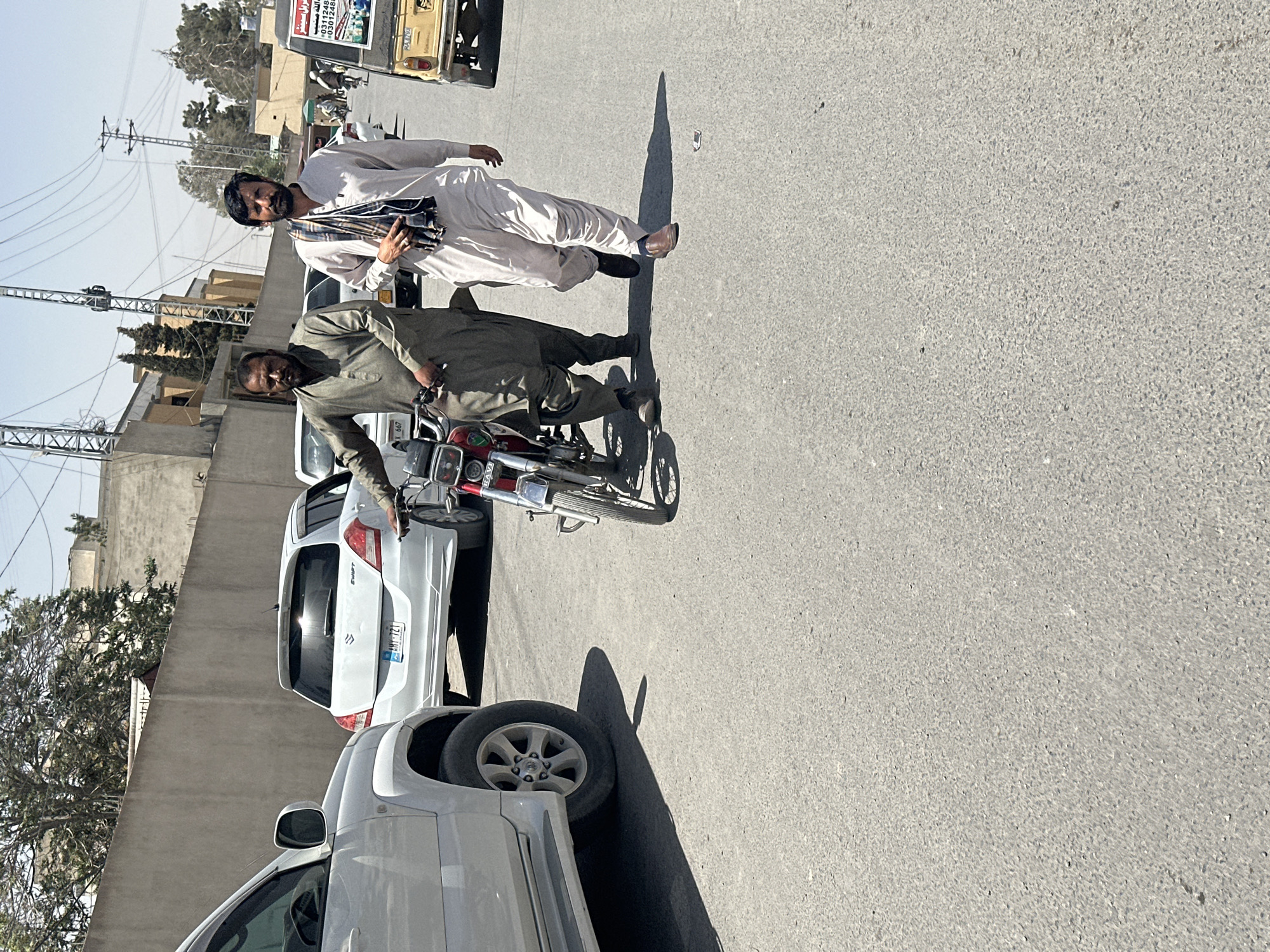 Morning street activity observed in Quetta: motorcycle conversation, cart transport