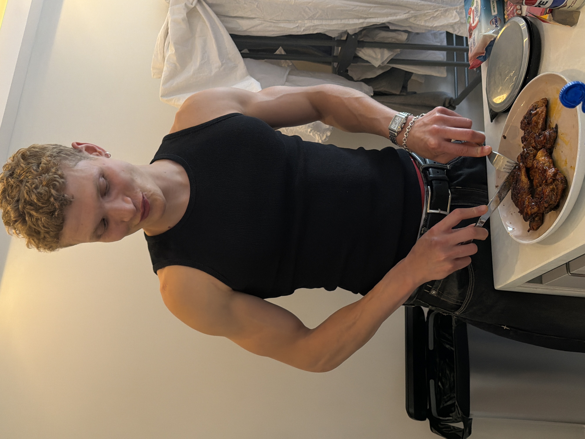 Young man cooks chicken meal in London apartment kitchen