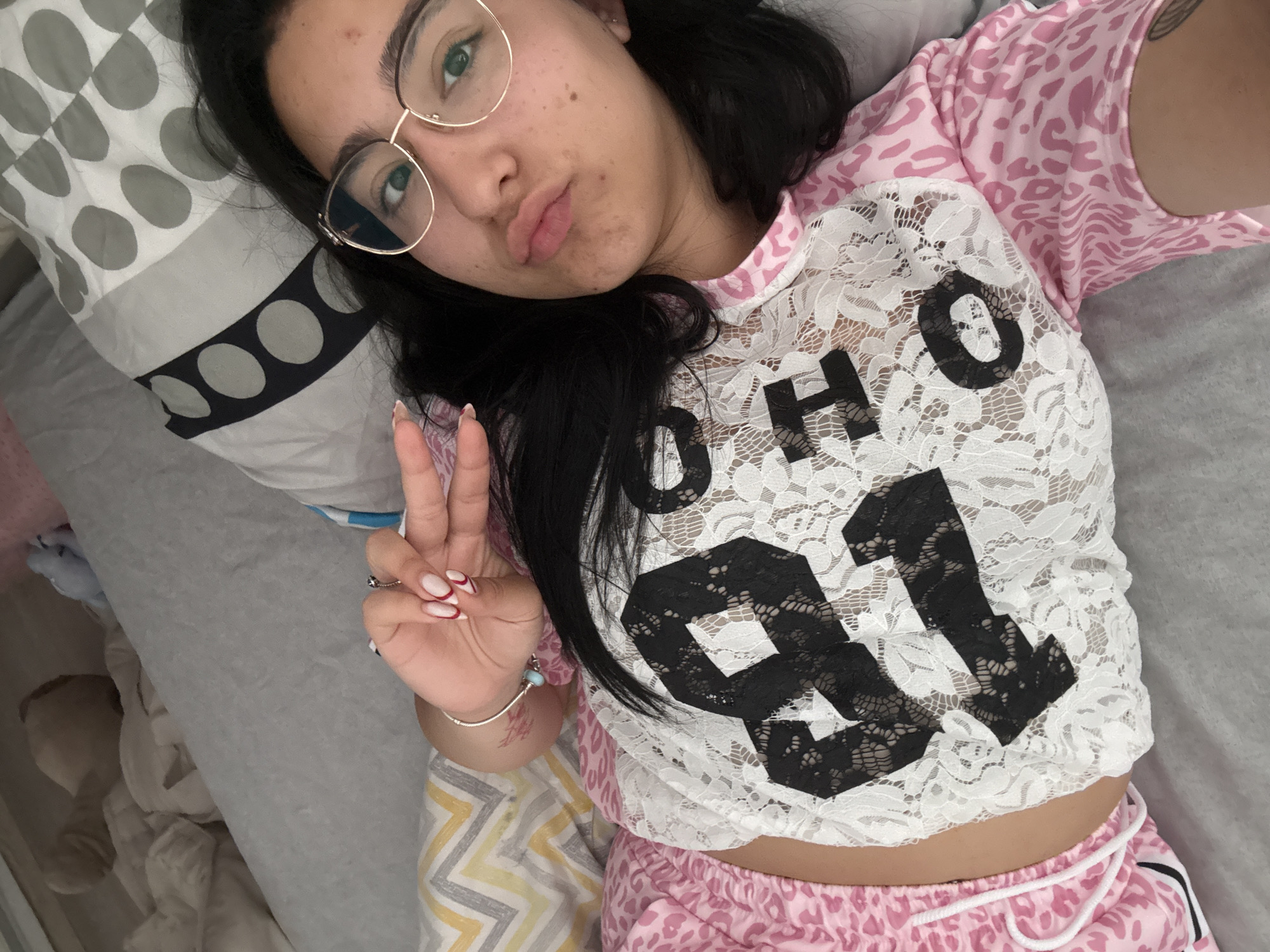 Woman makes peace sign gesture on bed in Elhovo
