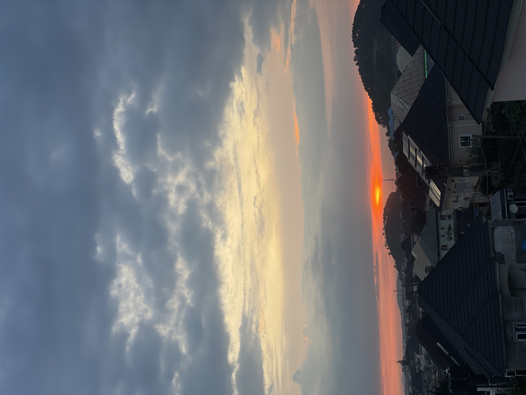 Abuja sunset over residential rooftops, late afternoon.