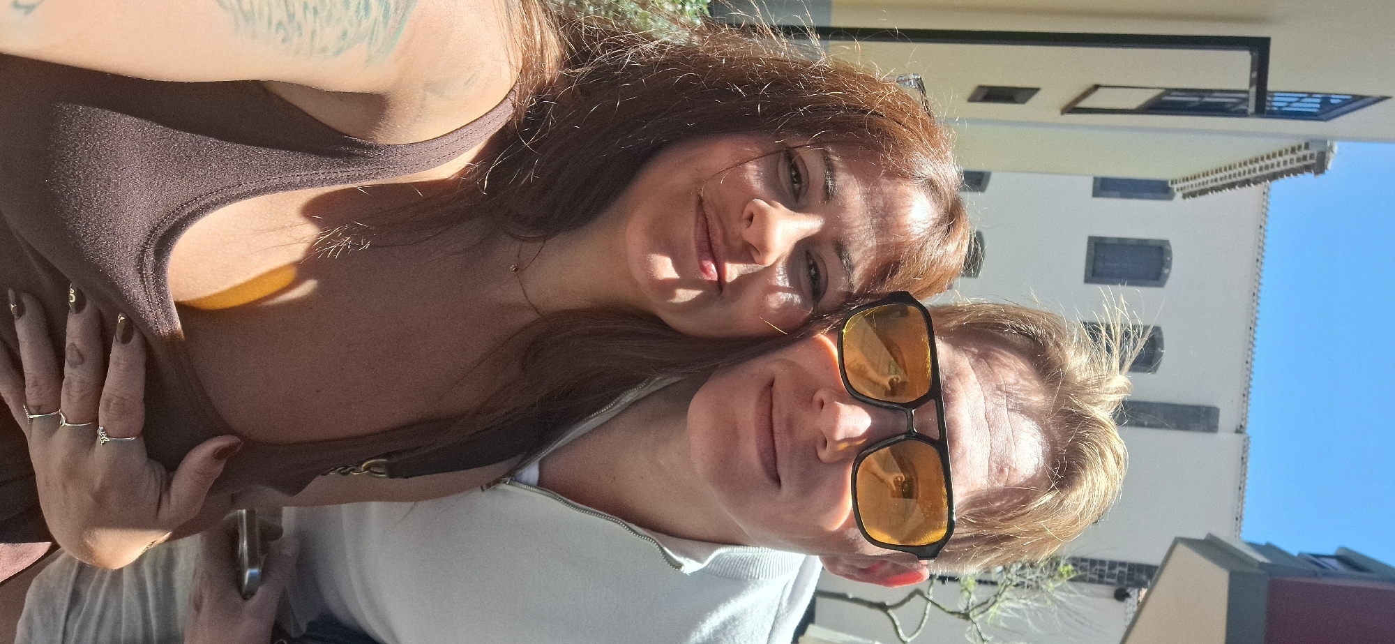 Two friends take selfies near bell tower on sunny day