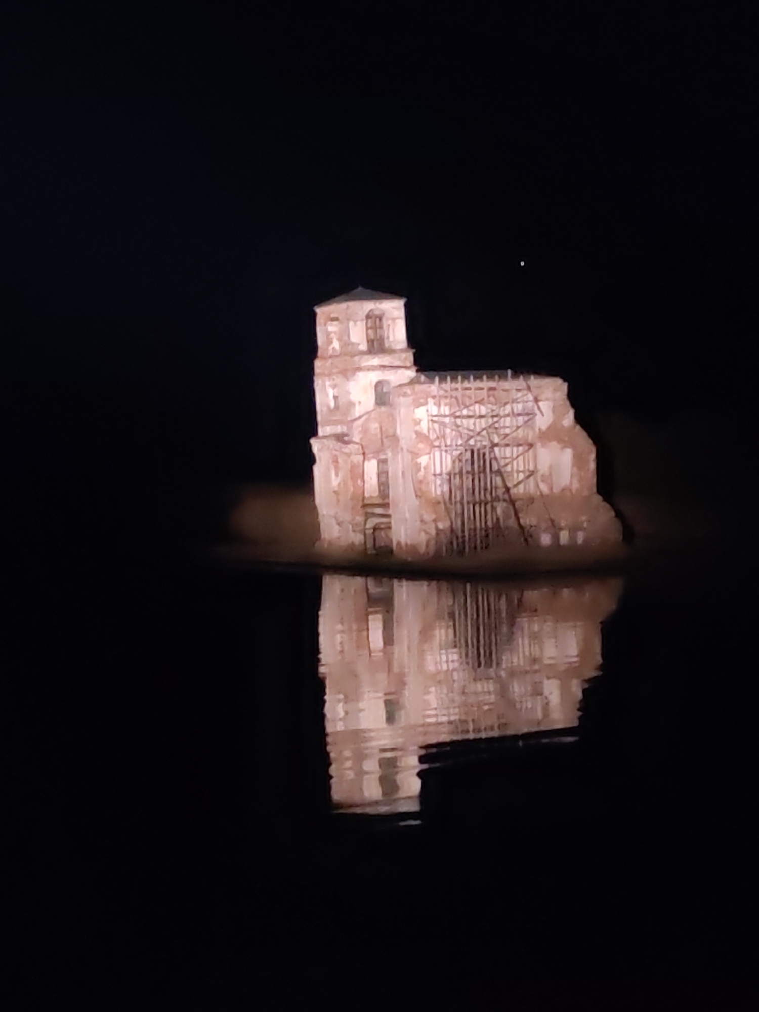 Illuminated church ruins glow in Krokhino waters at night