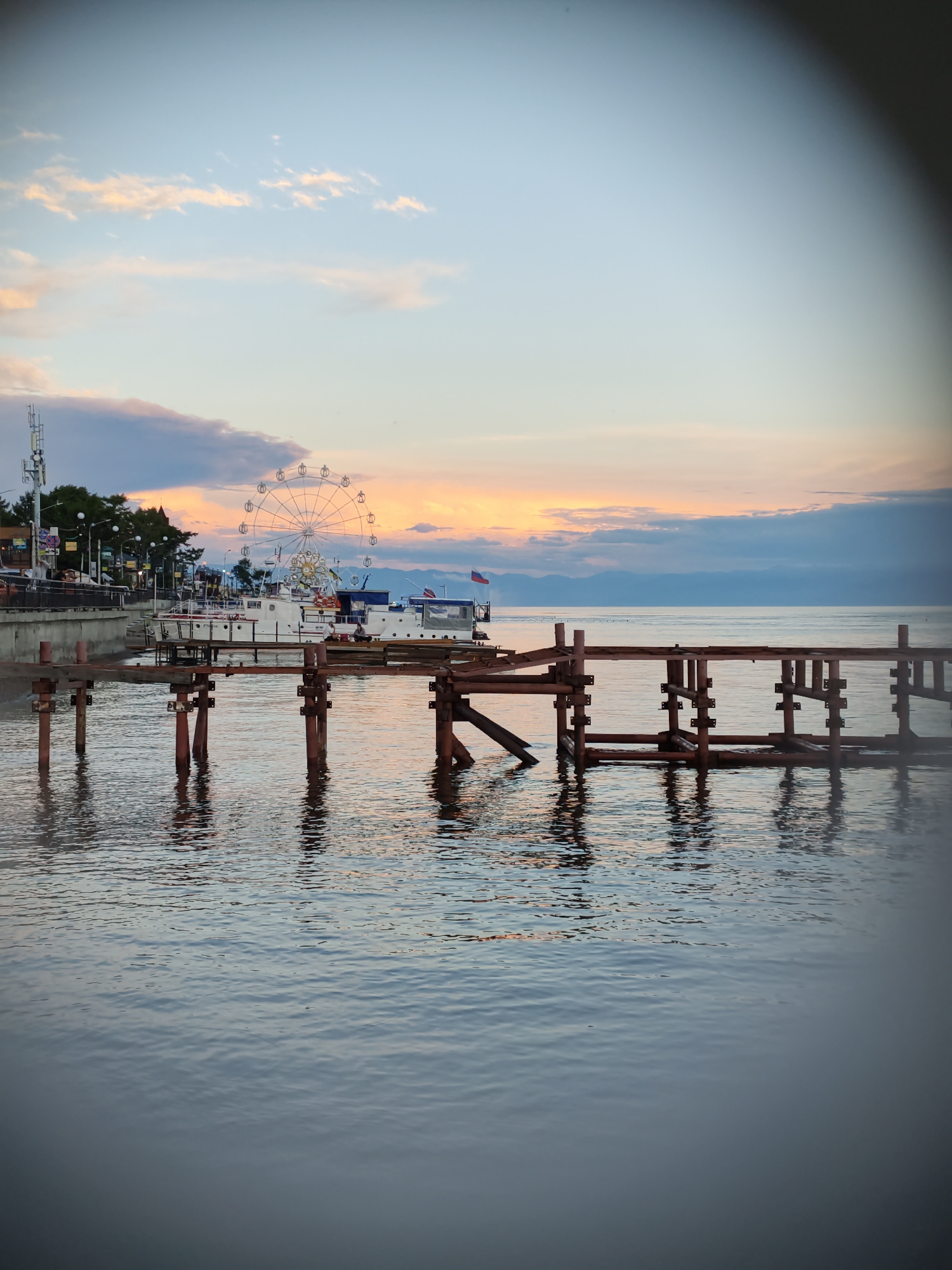 Dusk at Listvyanka's waterfront: pier, calm water, worn anchor