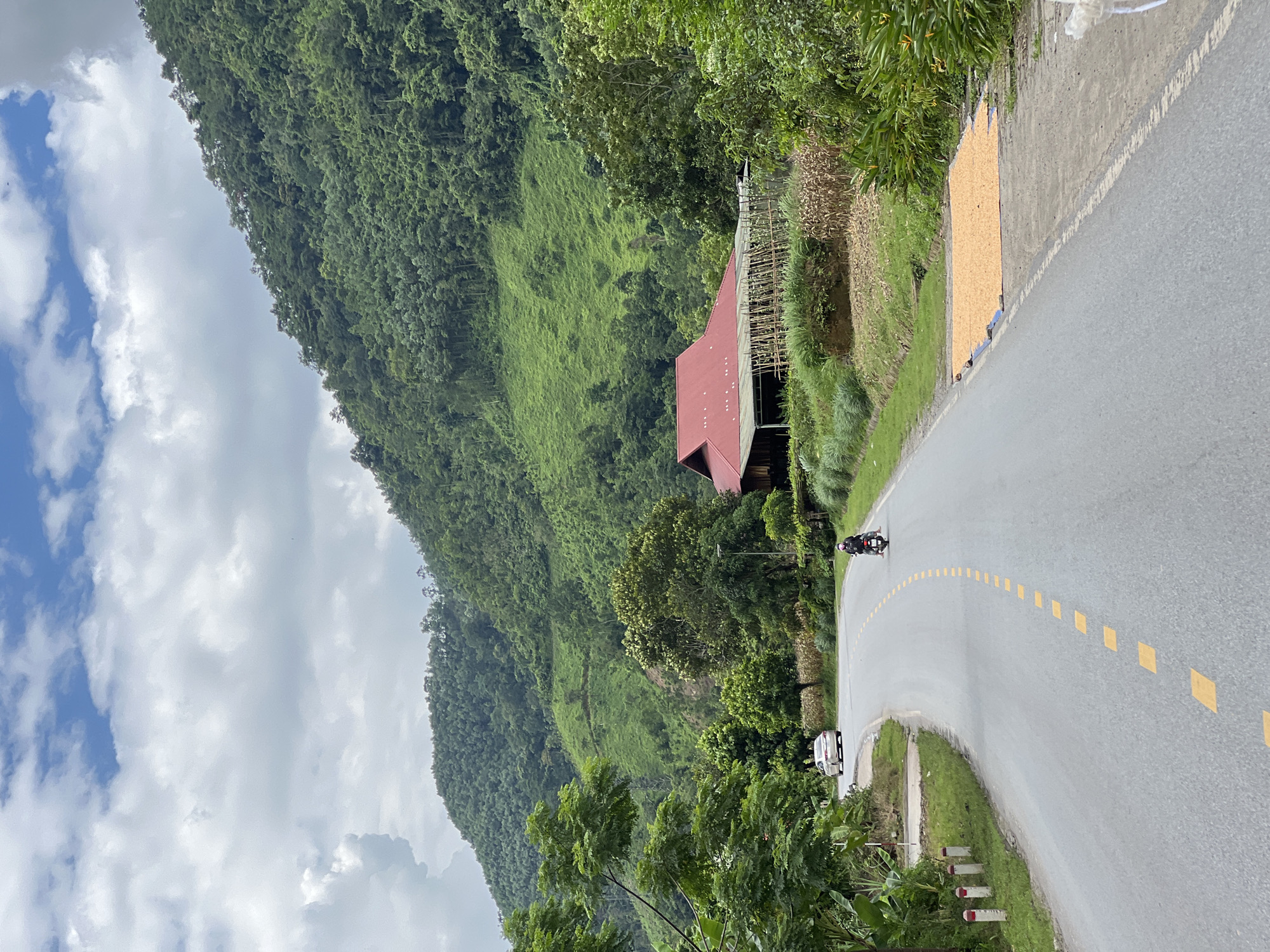 Winding mountain road past a red-roofed building in Thuận Hòa