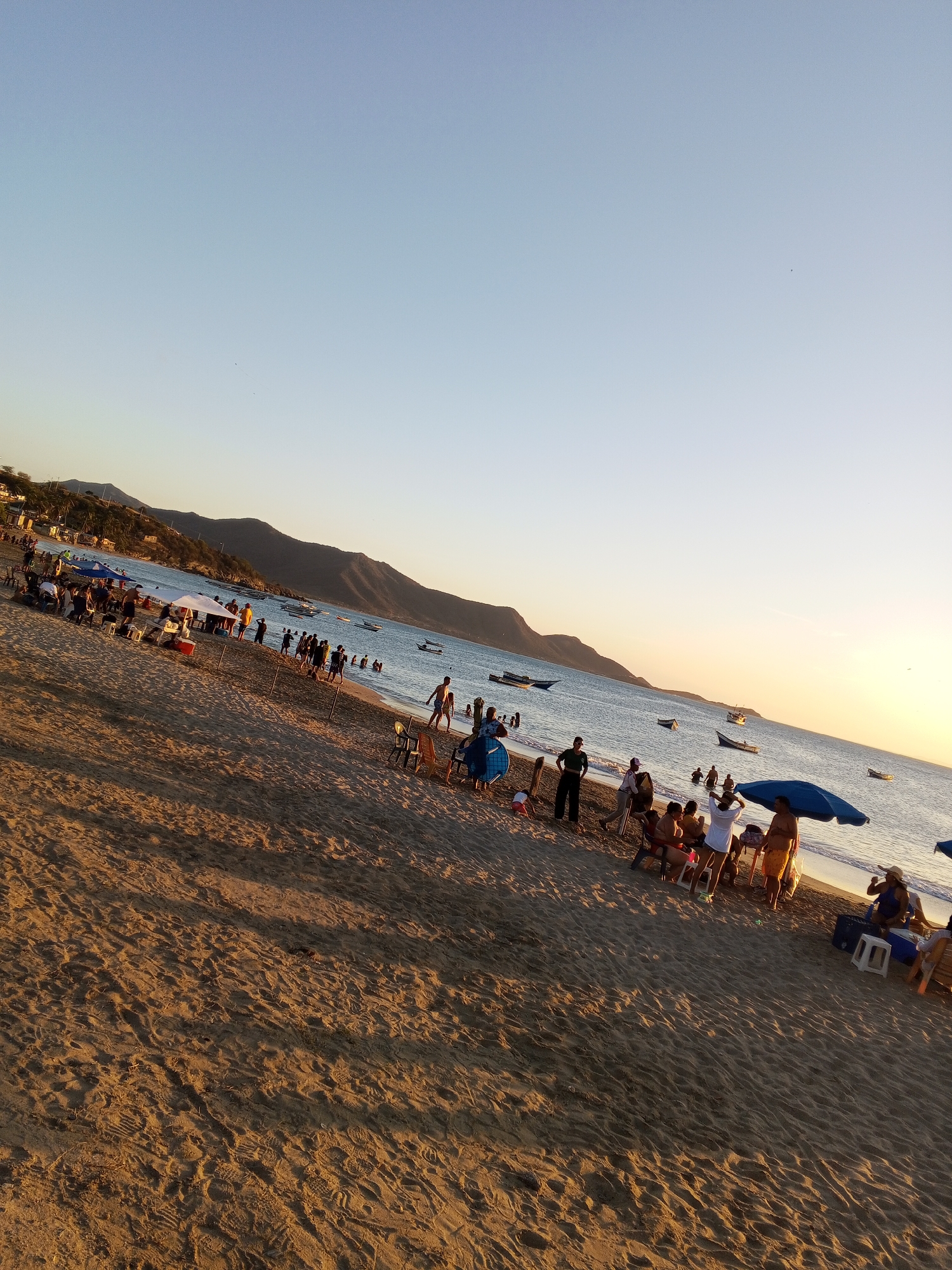 Beach gathering with cars and shade canopy in Juangriego