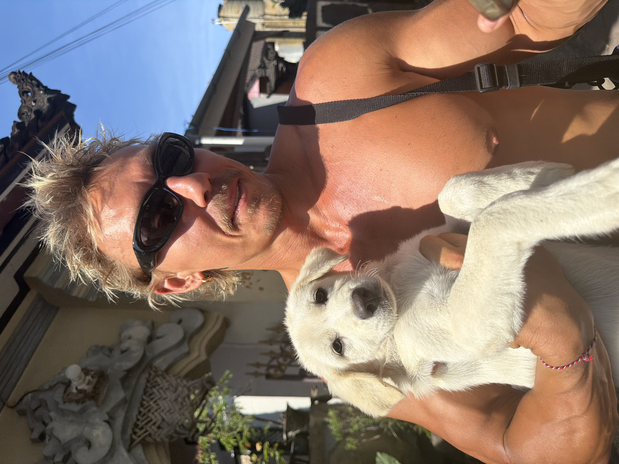 Tourist plays with white puppy in Mengwi, Indonesia