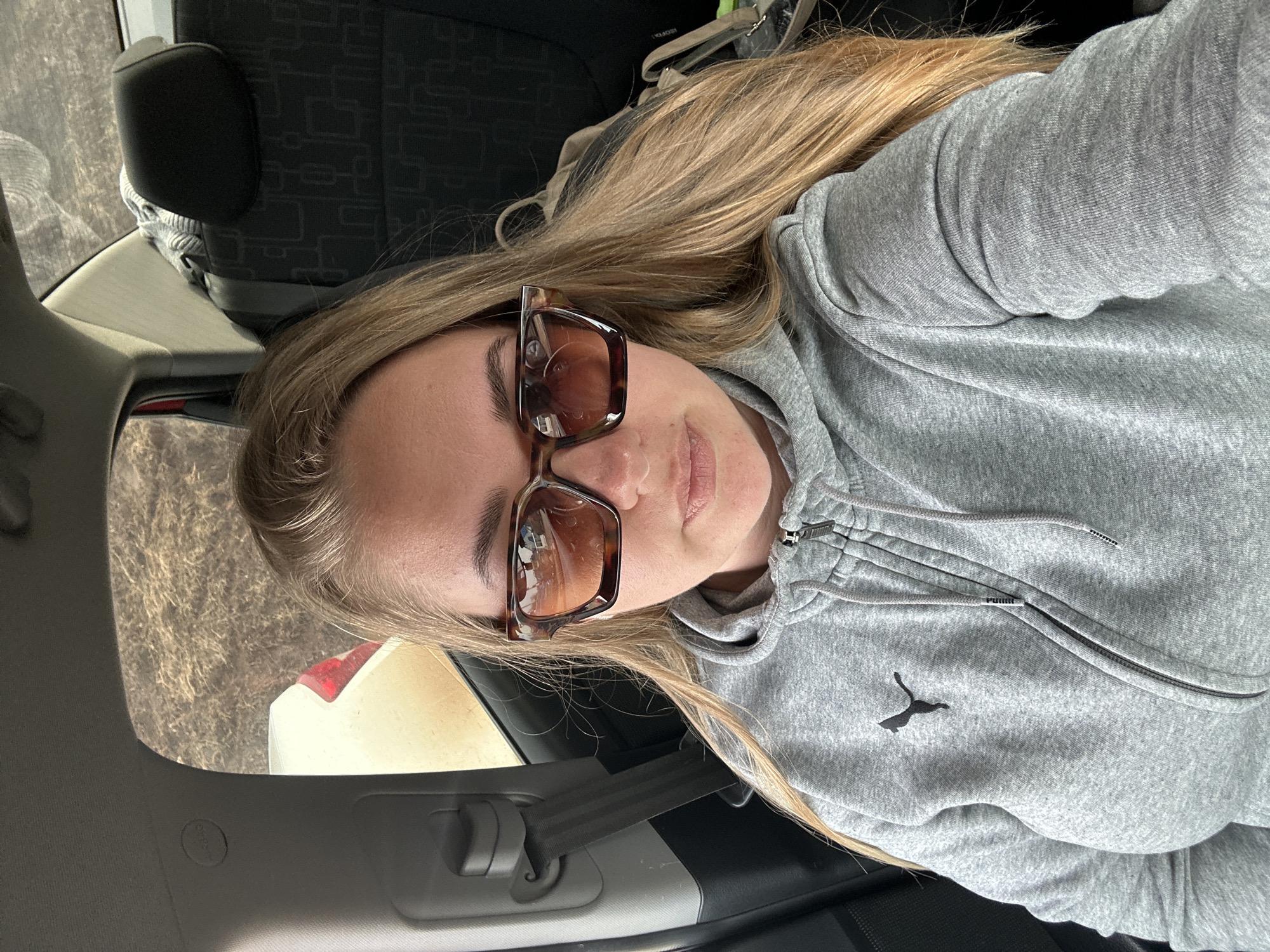 Woman in grey hoodie photographed inside car in Russia