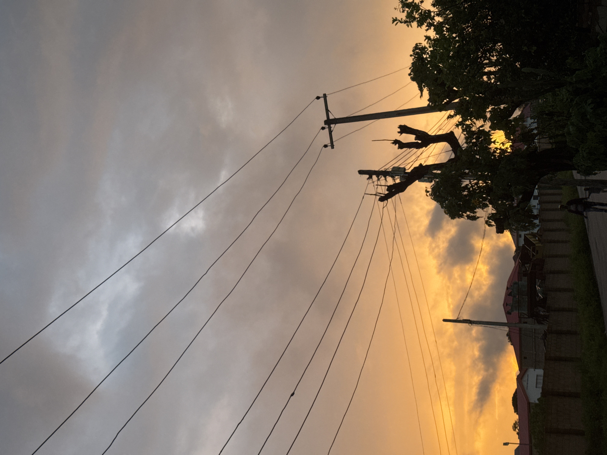 Vivid sunset breaks through dark clouds over a residential neighborhood