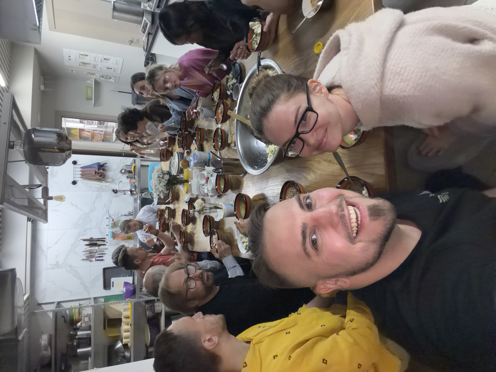 Dozen people share communal meal around wooden table in Moscow