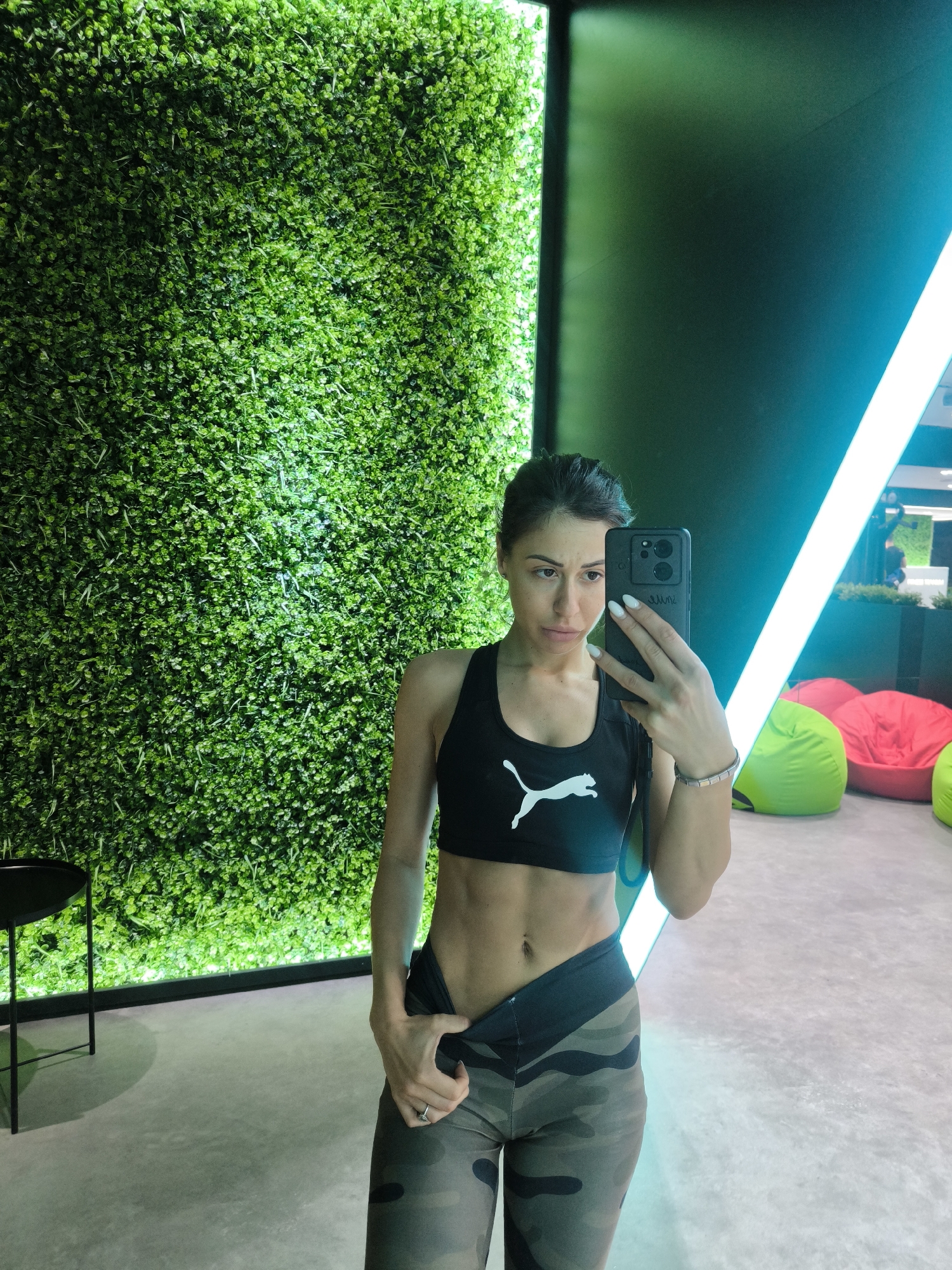 Person takes selfie against decorative wall with green foliage
