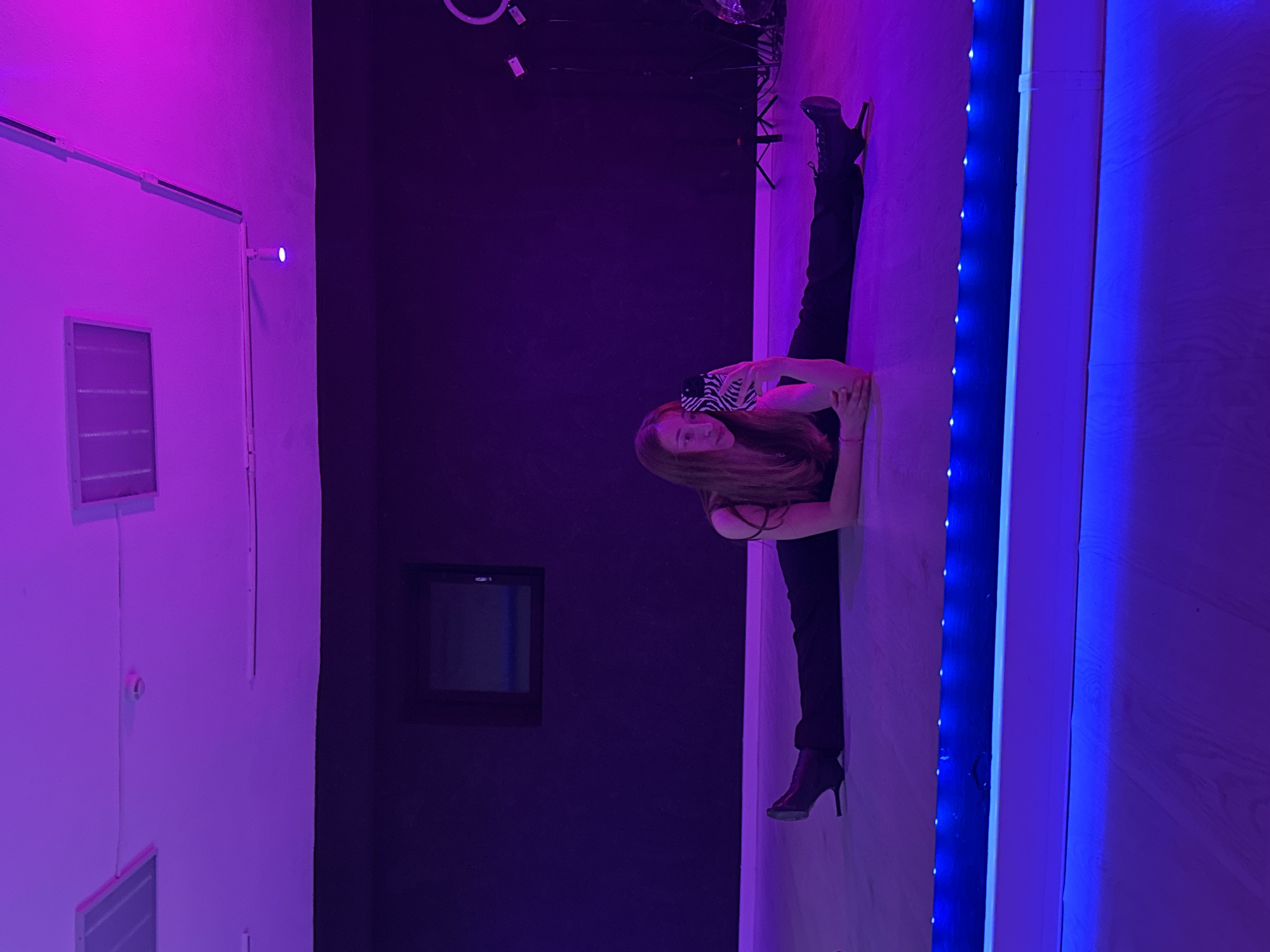 Woman takes selfies while stretching in neon-lit Chaikovsky room